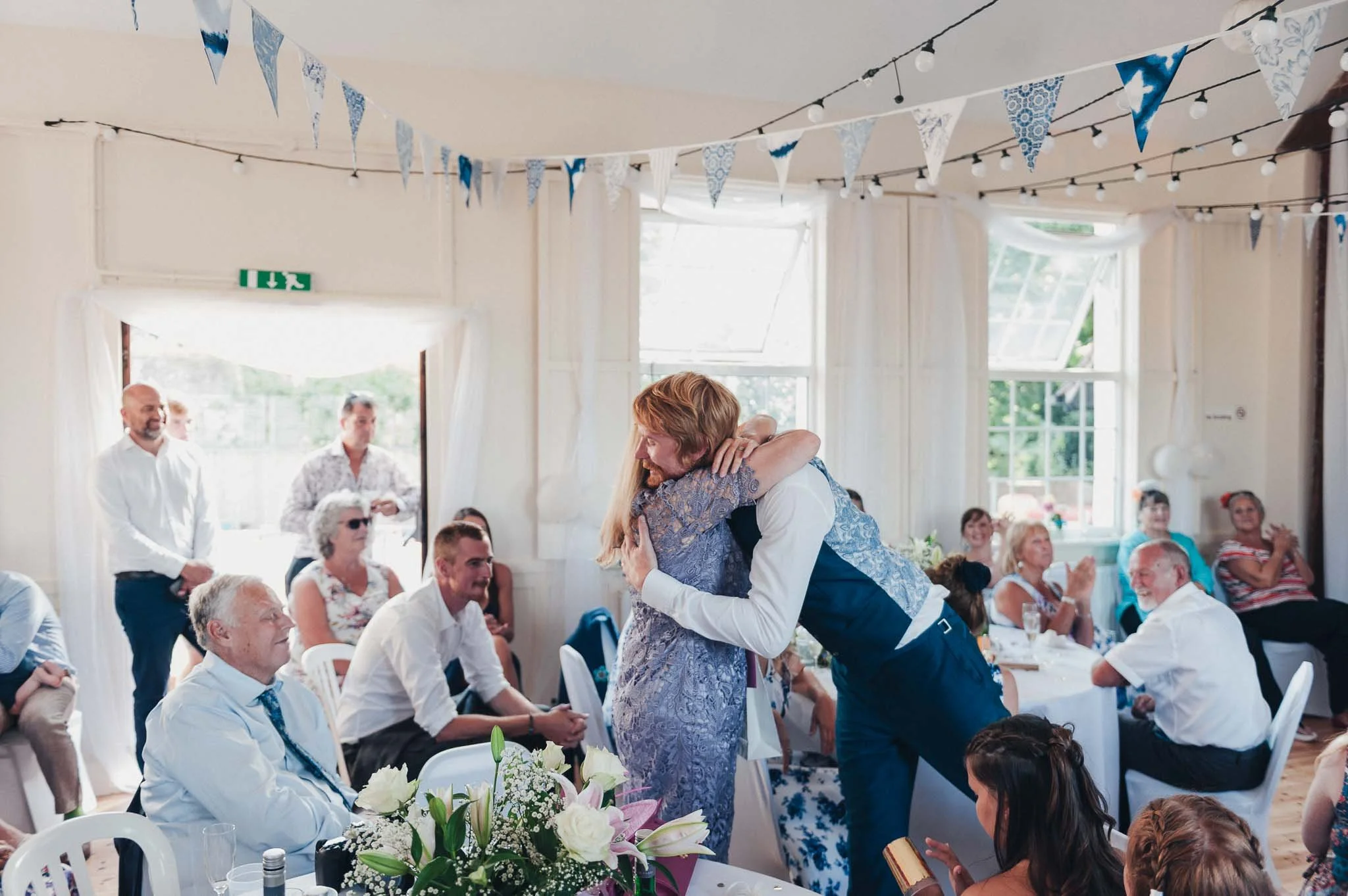The Groom hugging a guest tightly during the reception as others watch and smile.