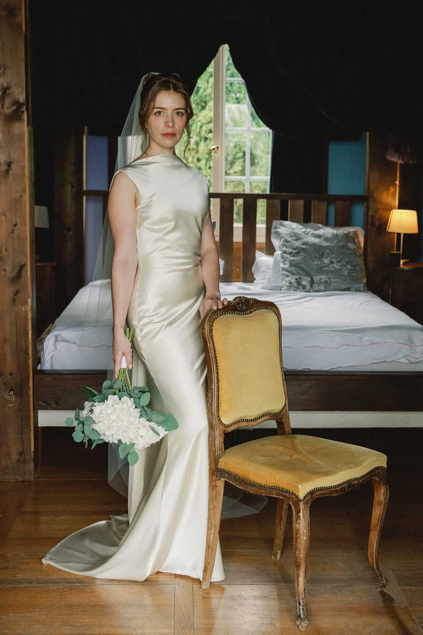 Full length portrait of the bride beside a gold chair at Château du Raysse, Dordogne