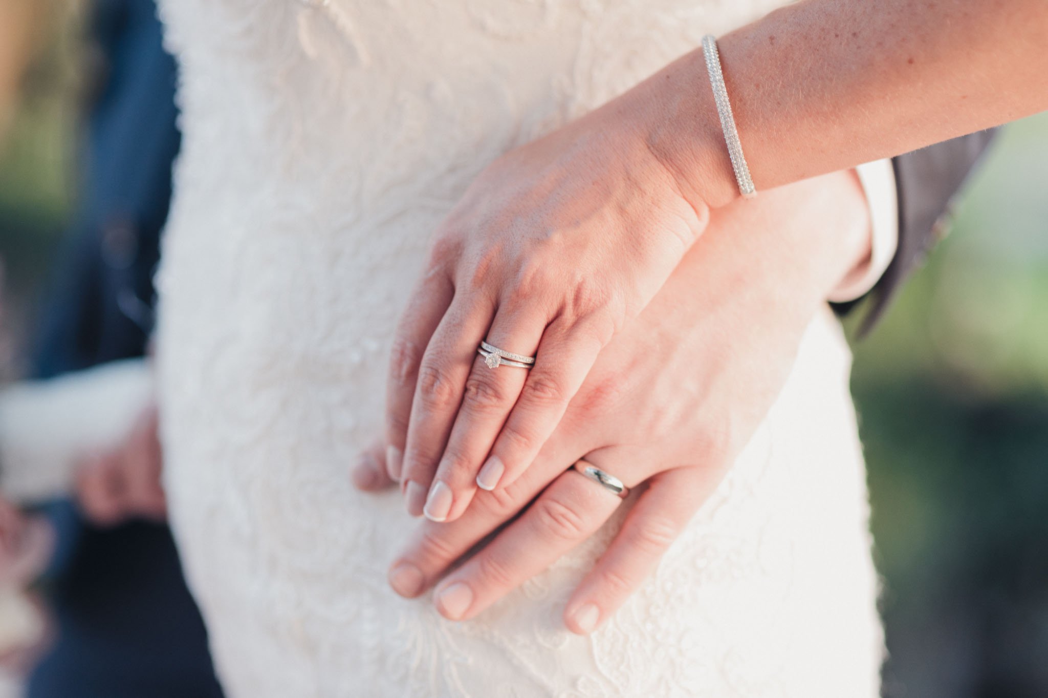 Close-up of the bride’s hand resting on the groom’s chest, showing her wedding ring.