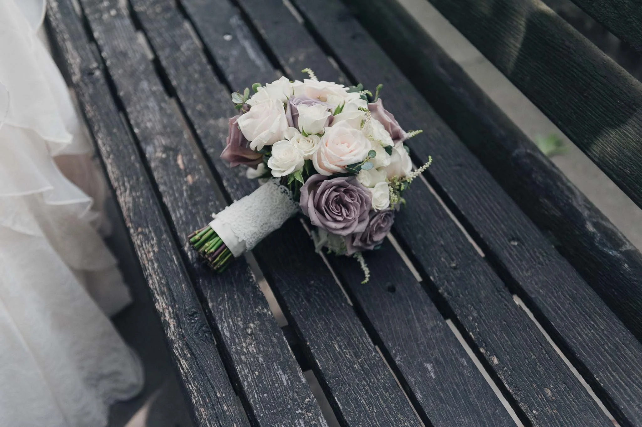 Bridal bouquet resting on a bench outdoors, photographed after the ceremony.