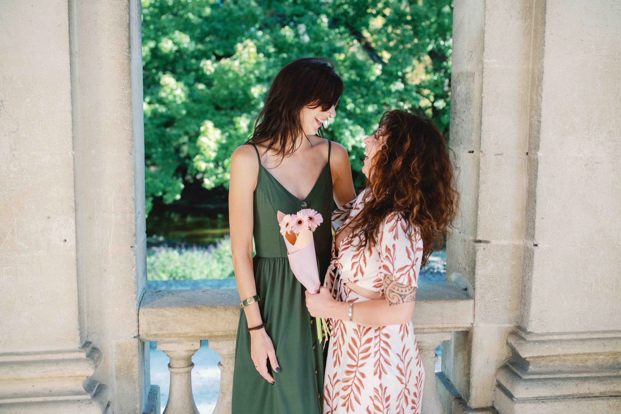 Couple laughing together with a bouquet of flowers after their proposal at the Palais in Jardin Public, Bordeaux