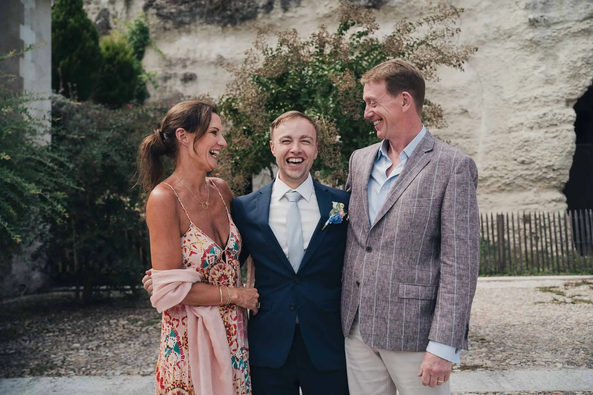 Groom laughing with two guests during the reception at Manoir de Longeveau.