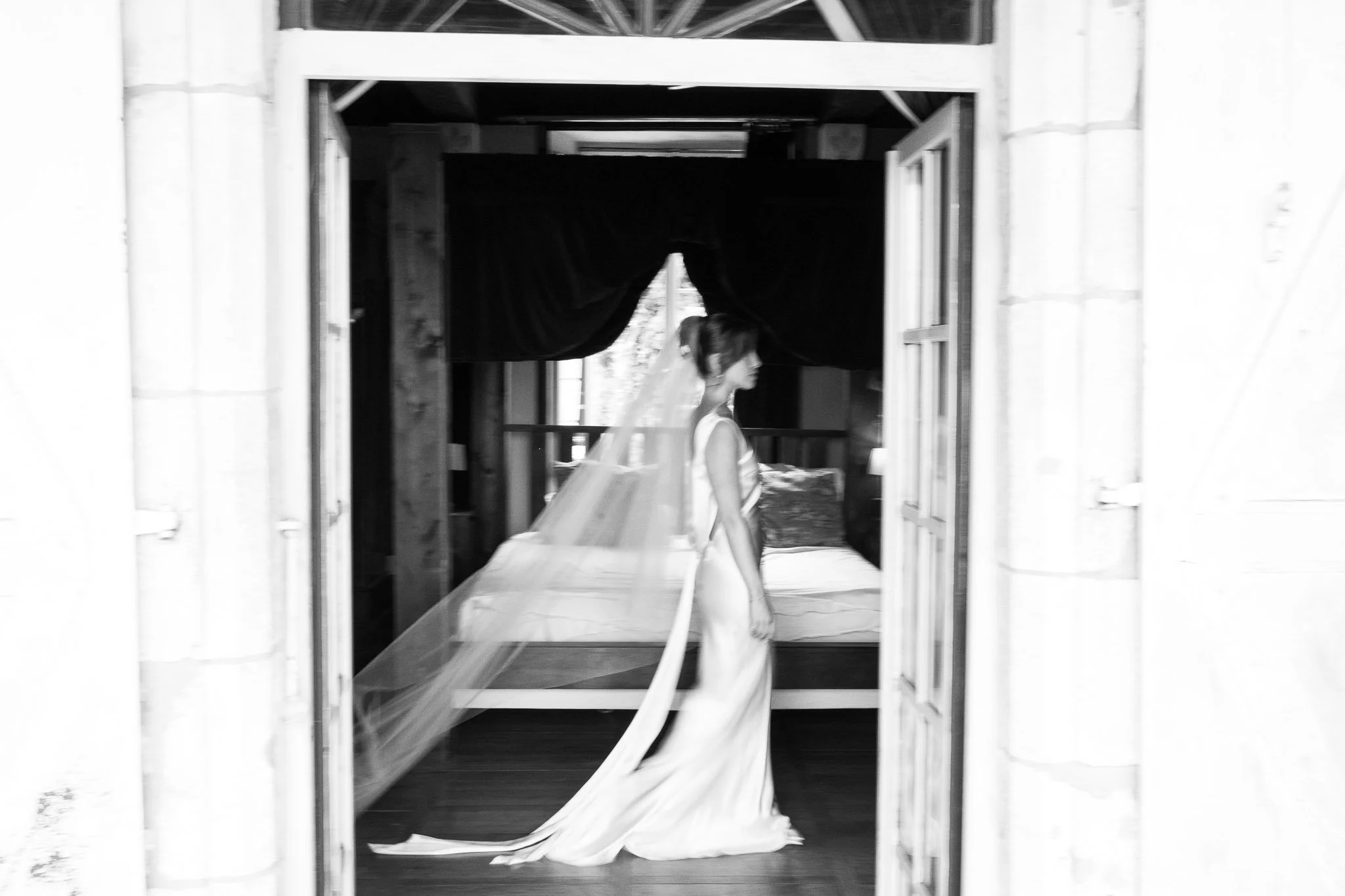 Bride in wedding dress standing in château doorway in black and white, Southwest France wedding photography