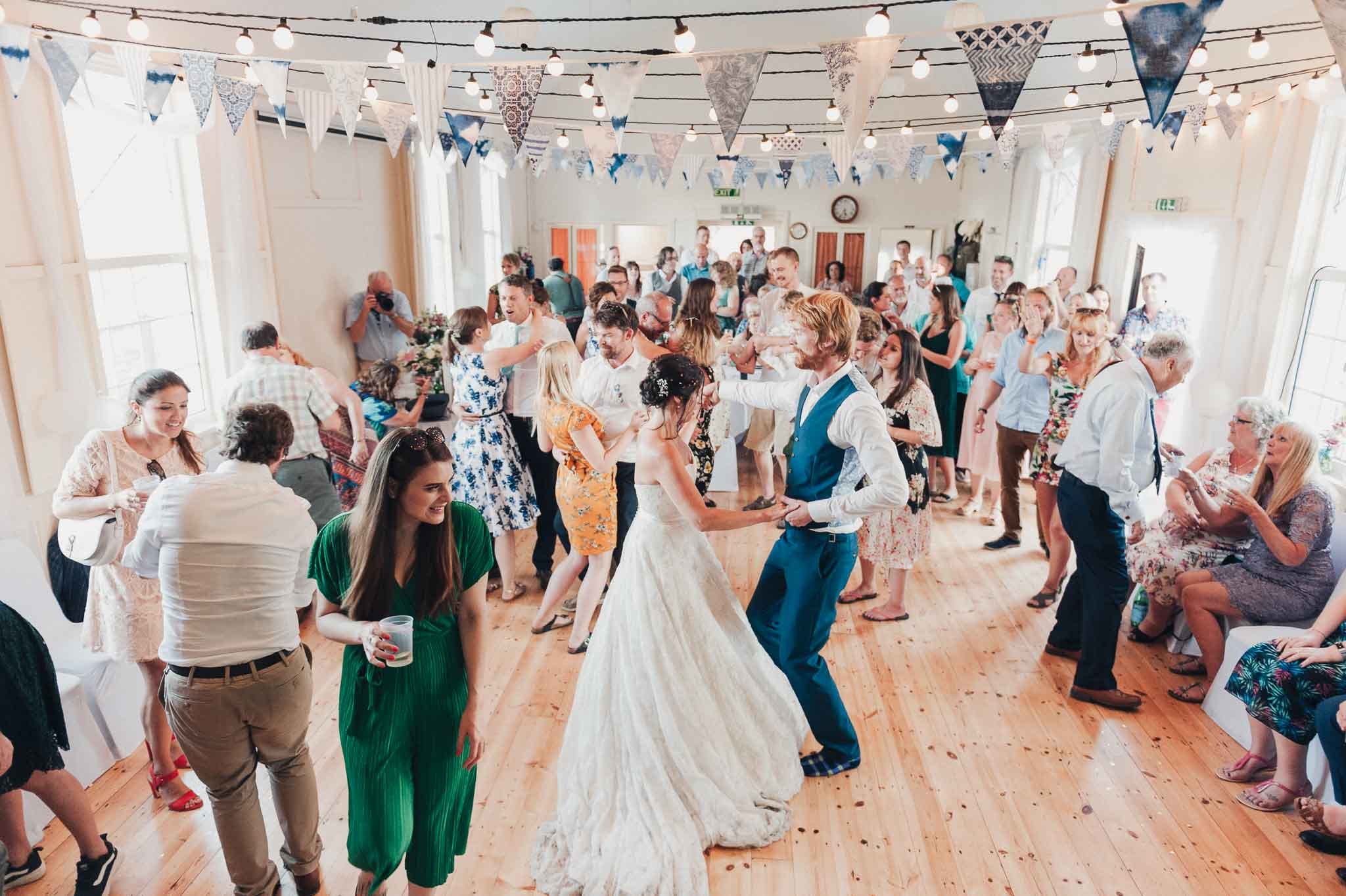 Guests dancing on the wooden floor of the village hall as the reception gets underway.