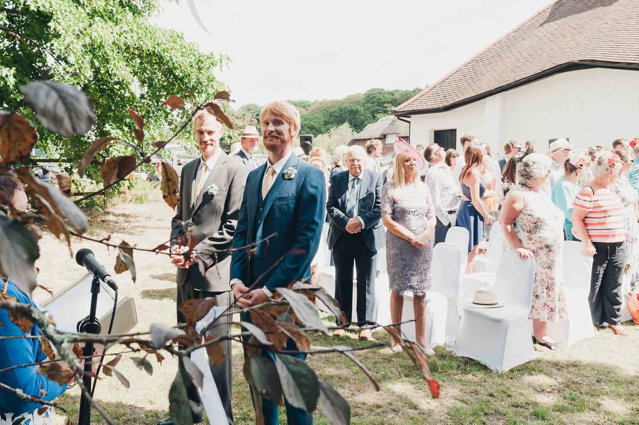 Guests seated outdoors as the groom and groomsmen wait at the front for the ceremony to begin.