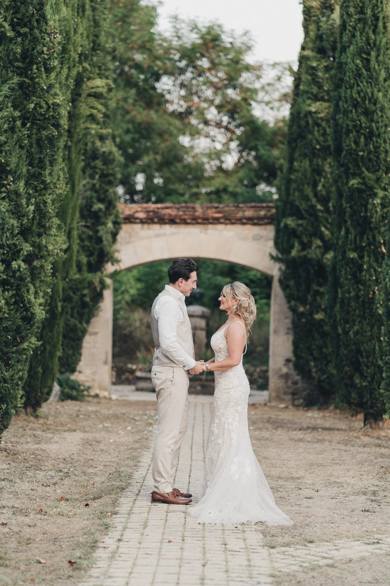 Couple standing together near a stone archway at their Dordogne wedding venue