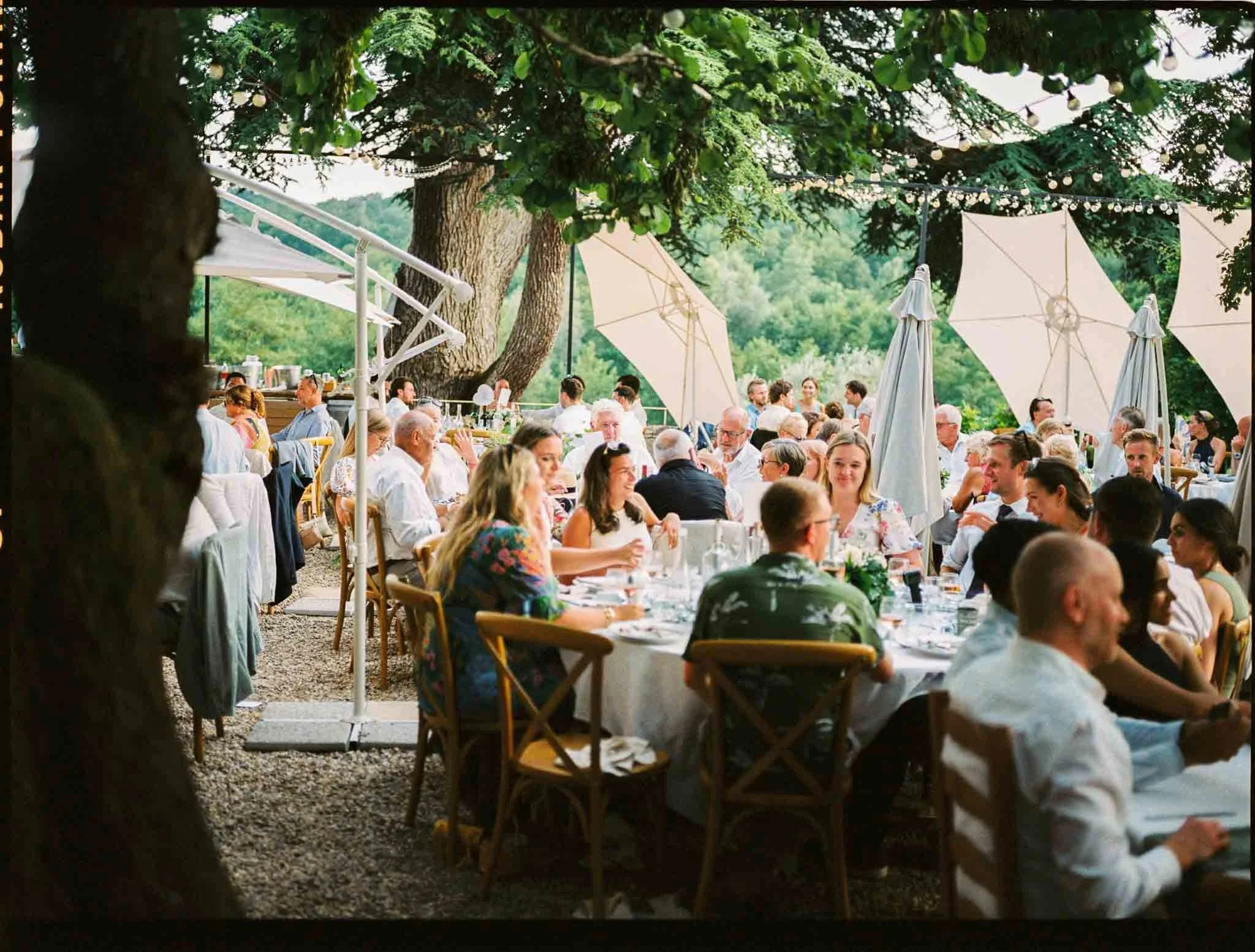 Medium format film photograph of a long wedding dinner table under trees at Château Lagorce, Bordeaux