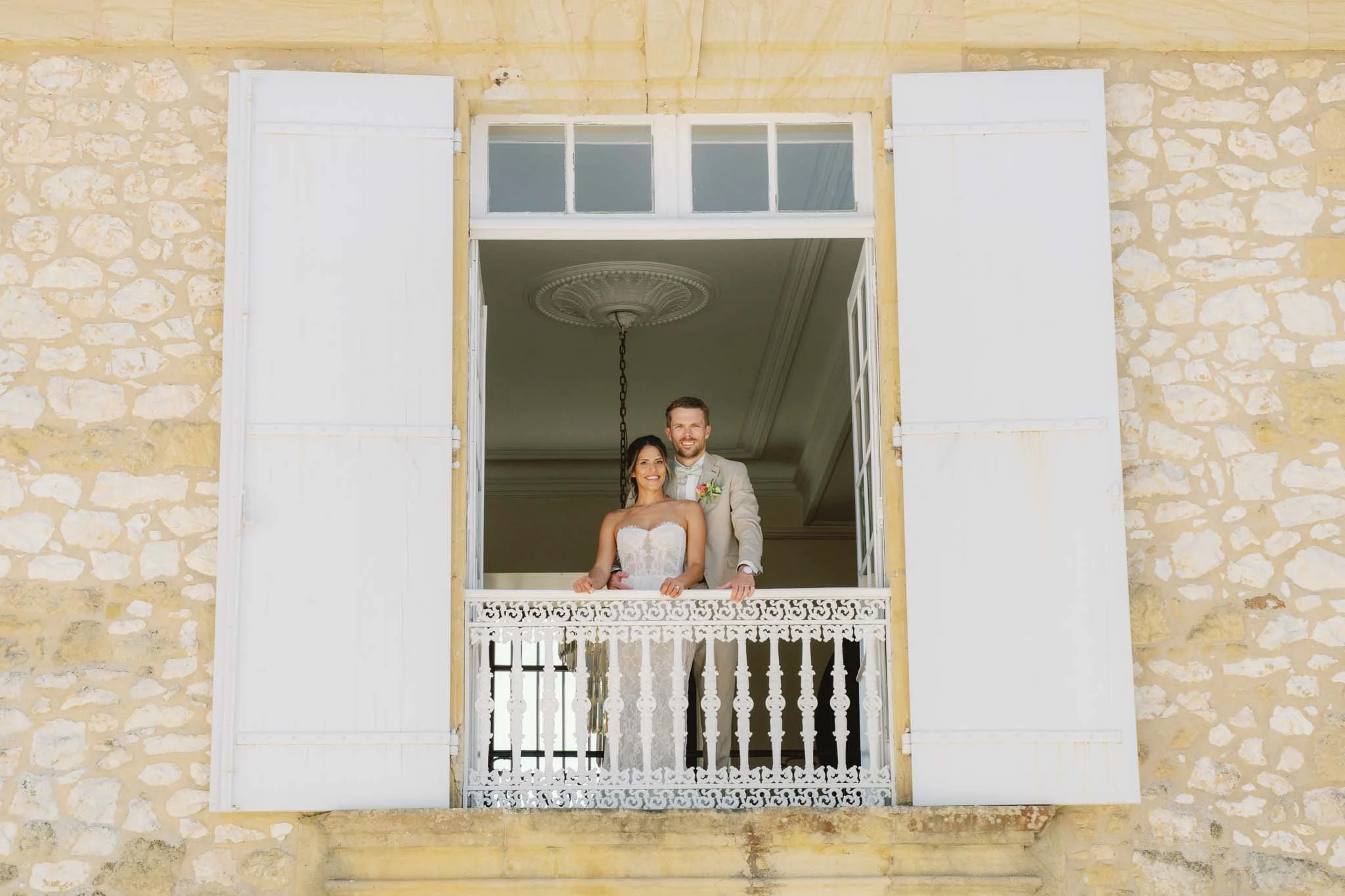 Bride and groom framed in a balcony window at Château de Sainte Croix, Dordogne