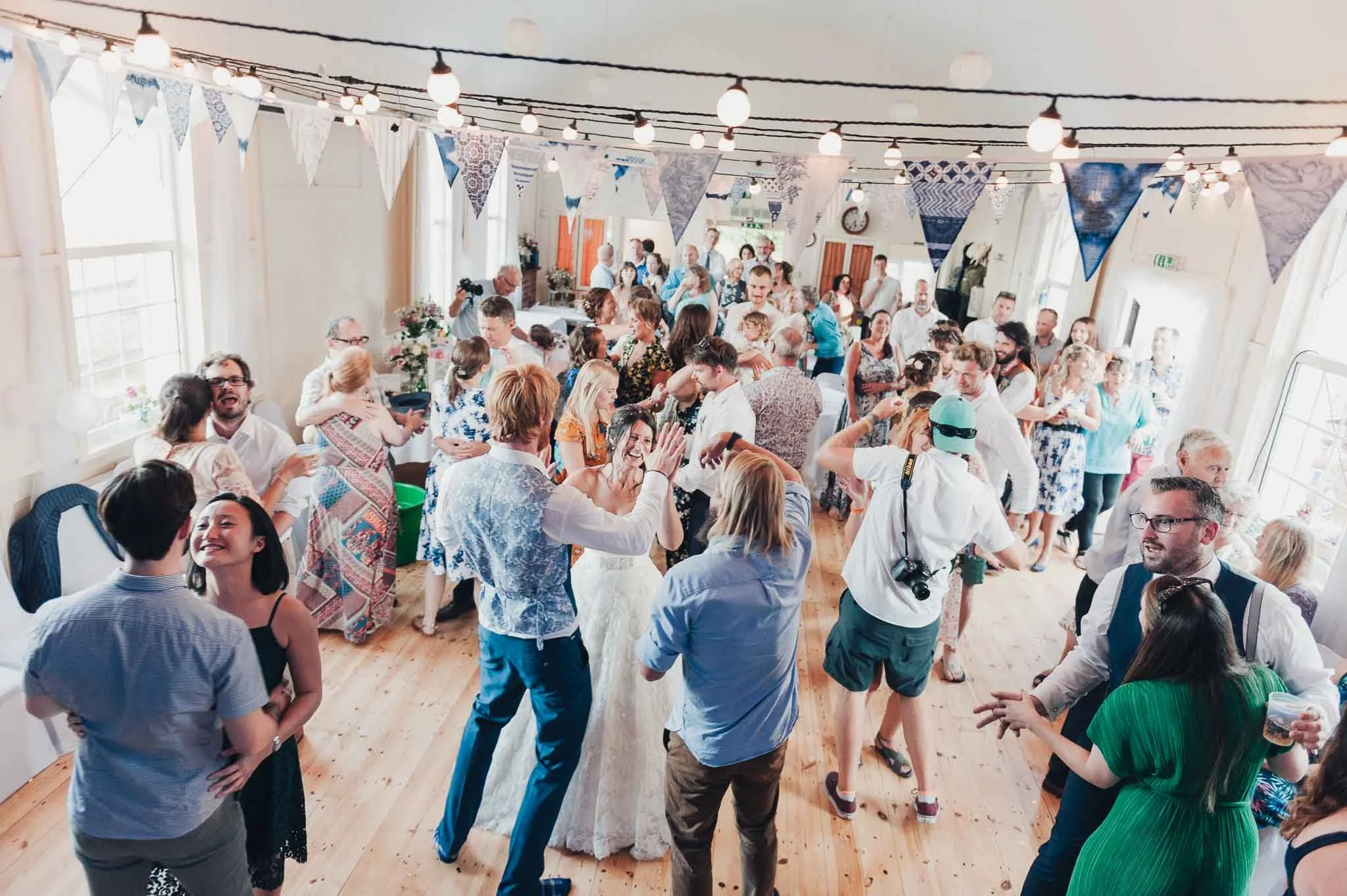 Wide view of the crowded dance floor with guests celebrating inside the decorated hall.