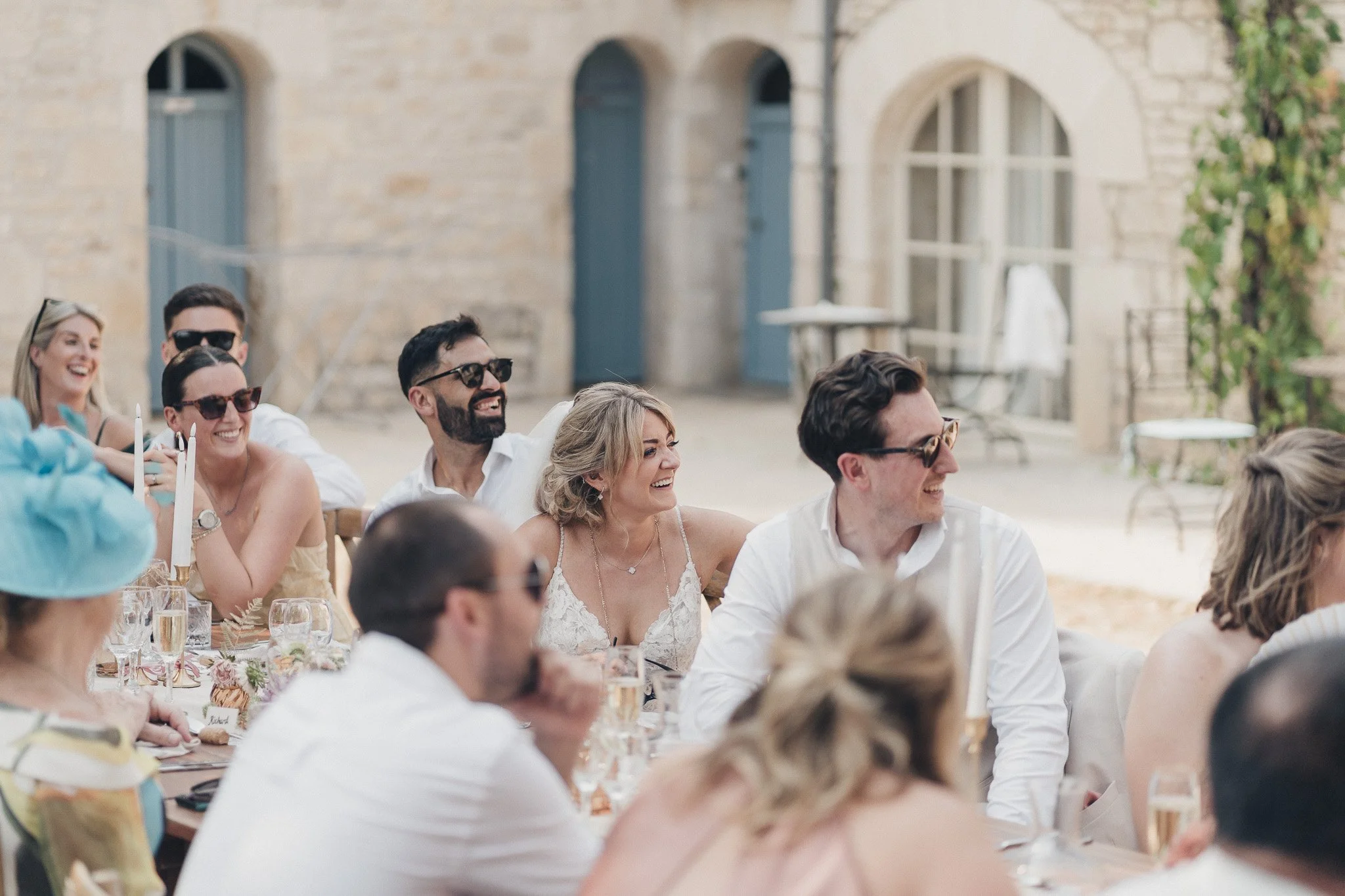 Bride and groom laughing together during a speech at their outdoor reception.