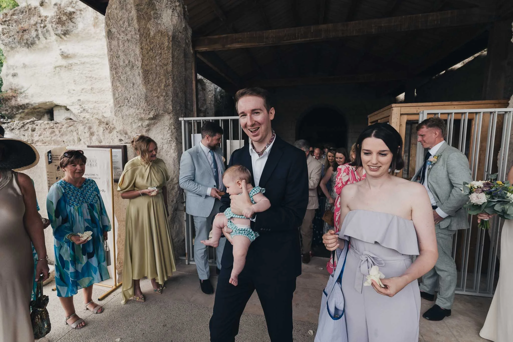 Guests leaving the church, including a couple carrying a baby, during the confetti moment setup.