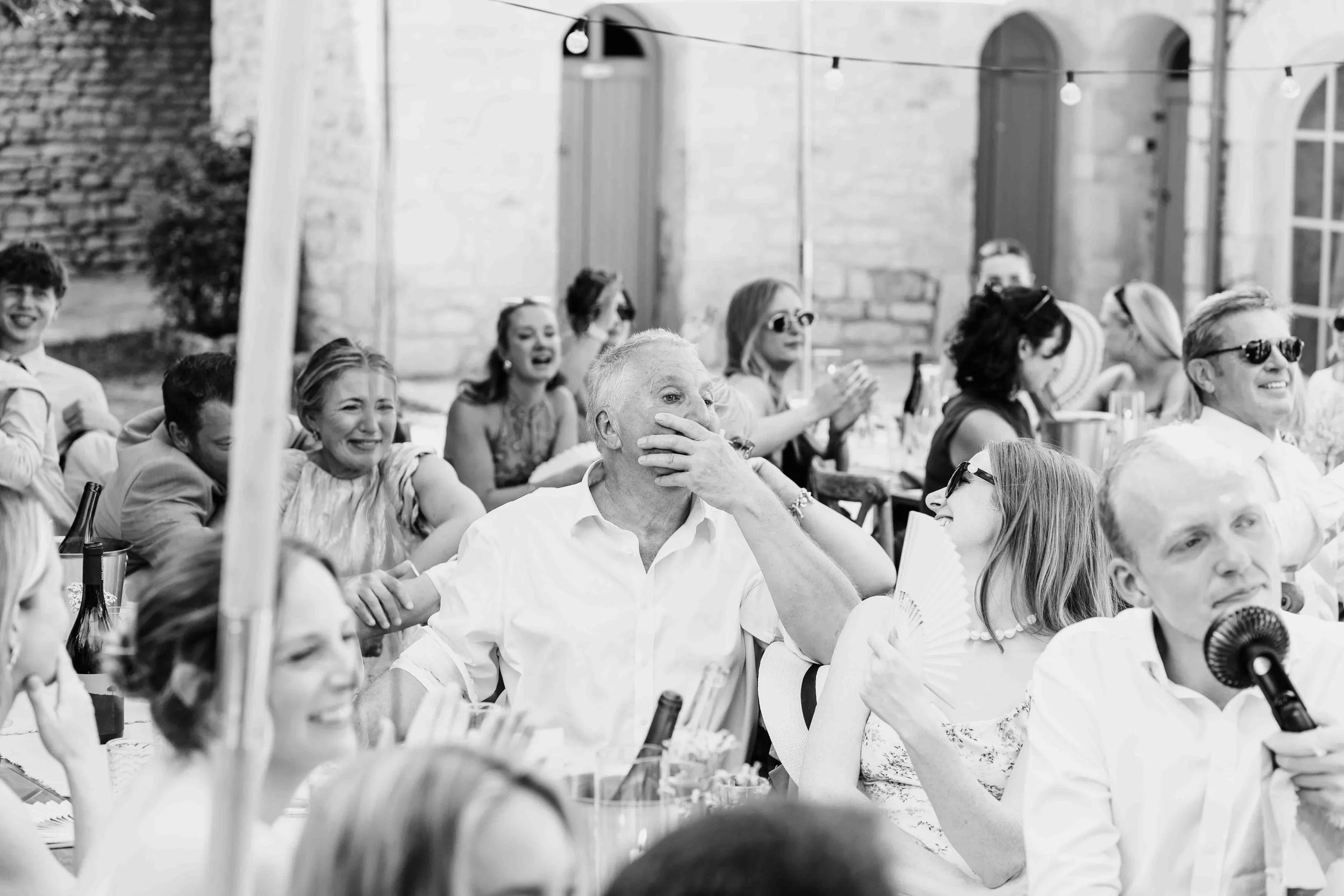 Father of the Groom reacting emotionally during a wedding speech, surrounded by friends and family