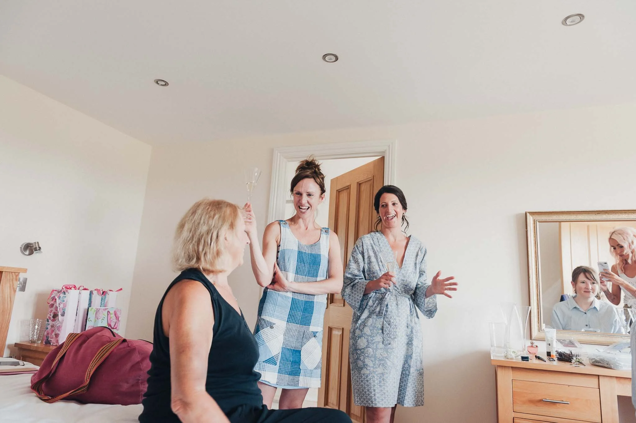 Bridesmaids chatting and laughing in the bedroom as everyone gets ready for the ceremony.