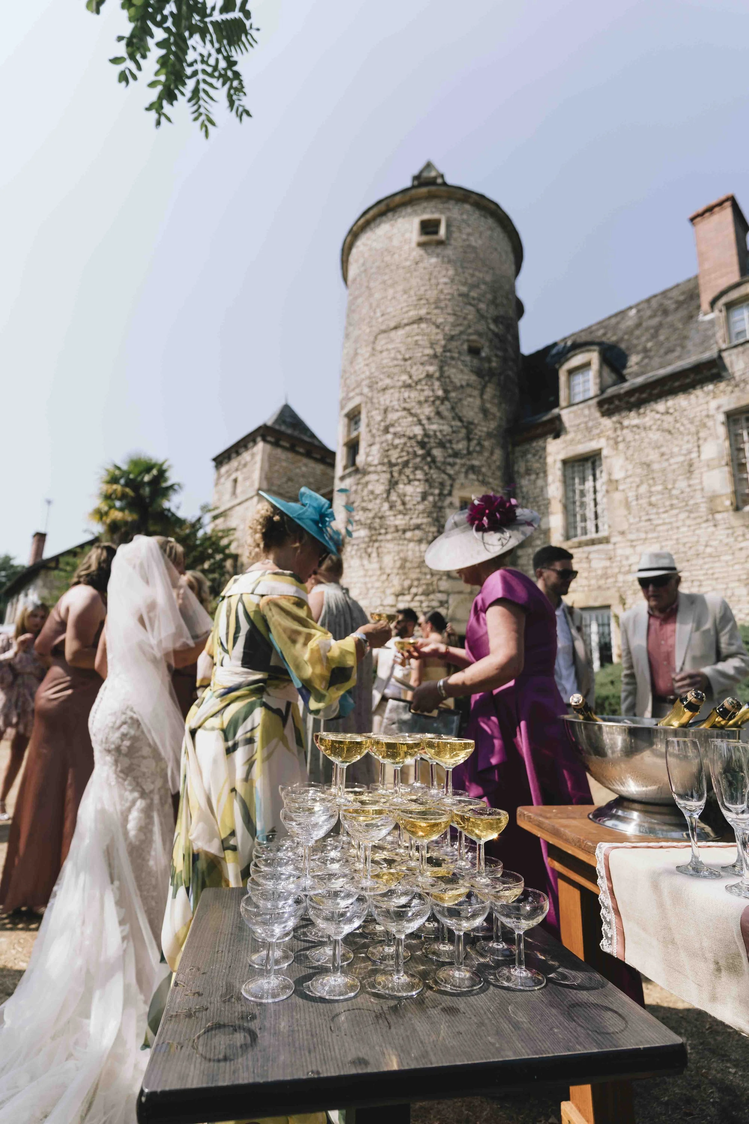 Guests enjoying champagne outside a Dordogne château during cocktail hour at a French wedding.