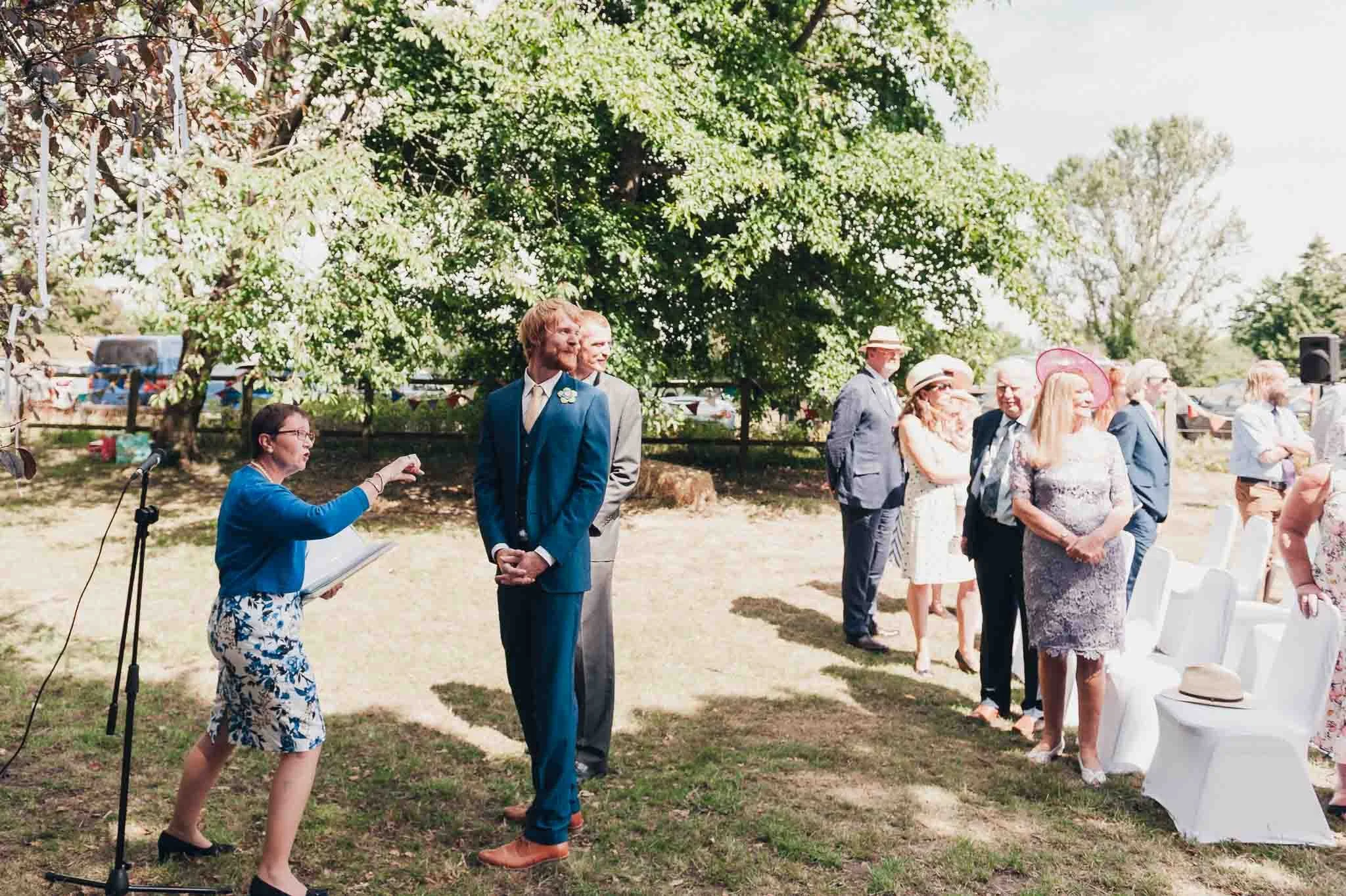 The groom smiling as a guest takes a photo before the ceremony starts.