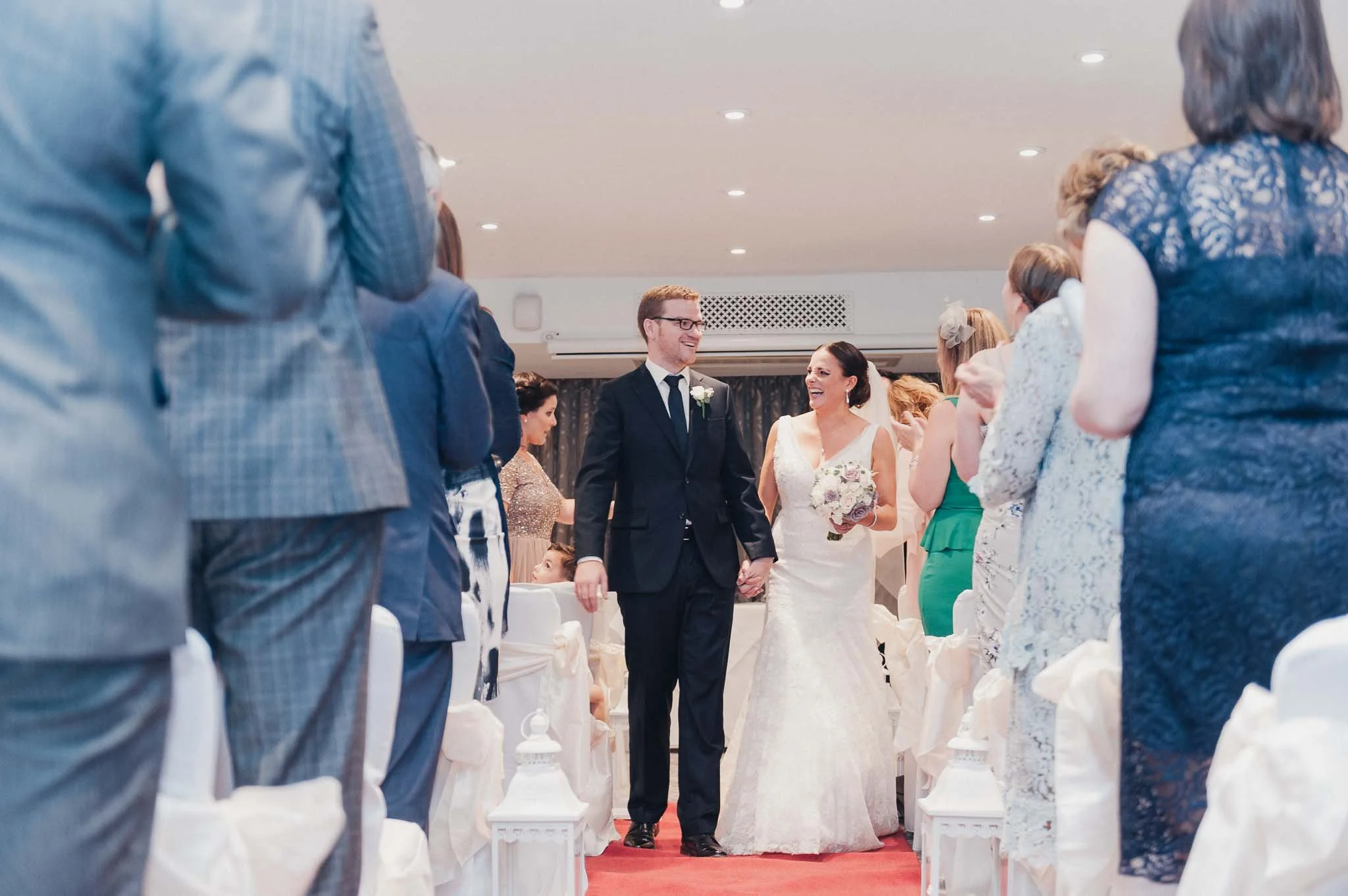 Bride and groom walking back up the aisle together after the ceremony, smiling at their guests.