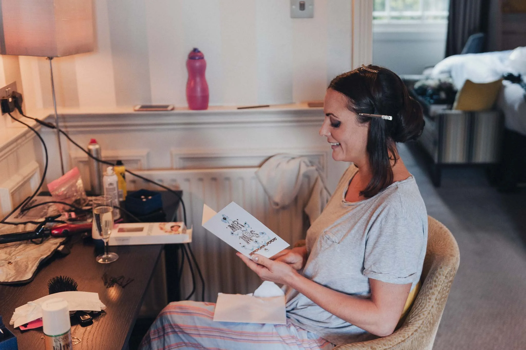 Bride smiling as she reads a wedding-day card during the morning getting-ready session.