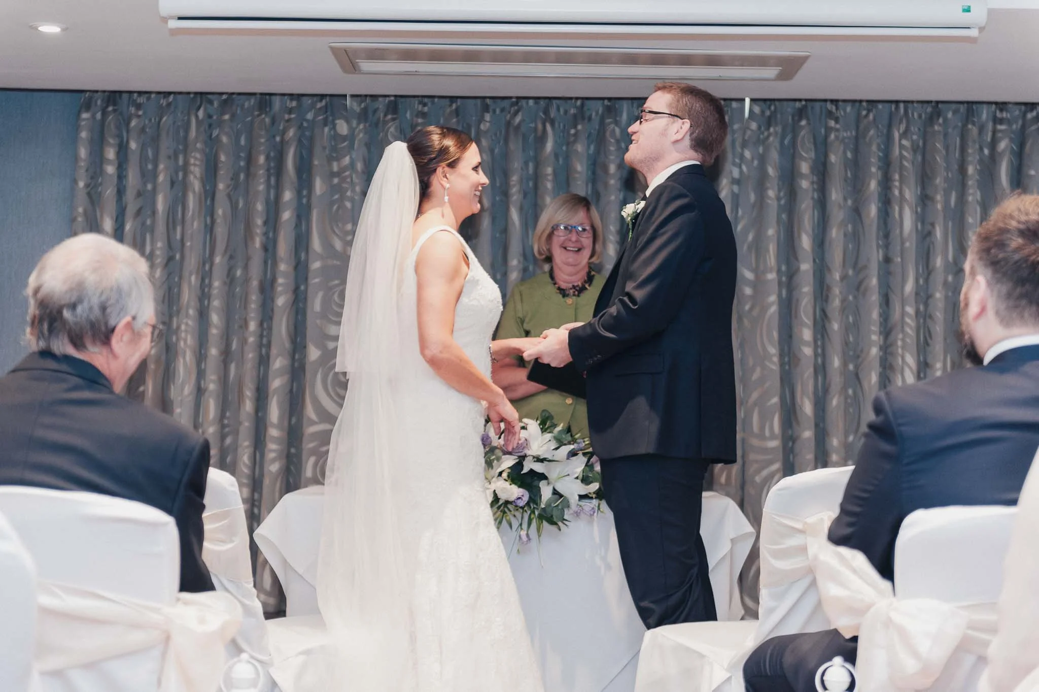 Bride and groom standing together during the indoor wedding ceremony, exchanging vows.