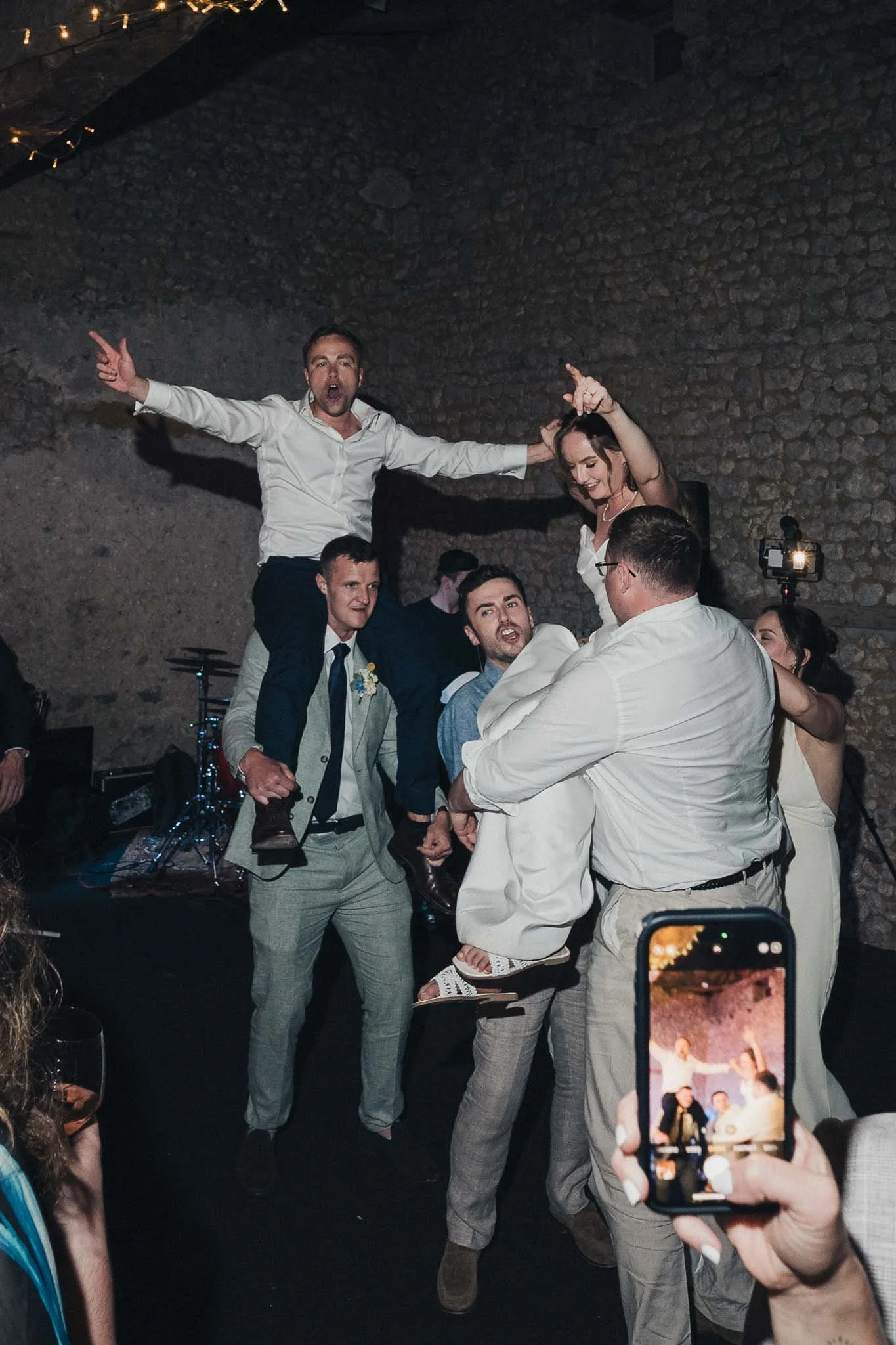 Groom and guests being lifted into the air together during a lively dancefloor moment.