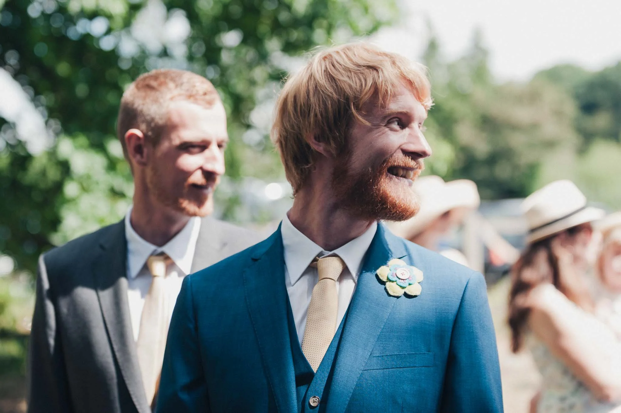 The groom smiling and looking to the side while standing with his best man before the ceremony.