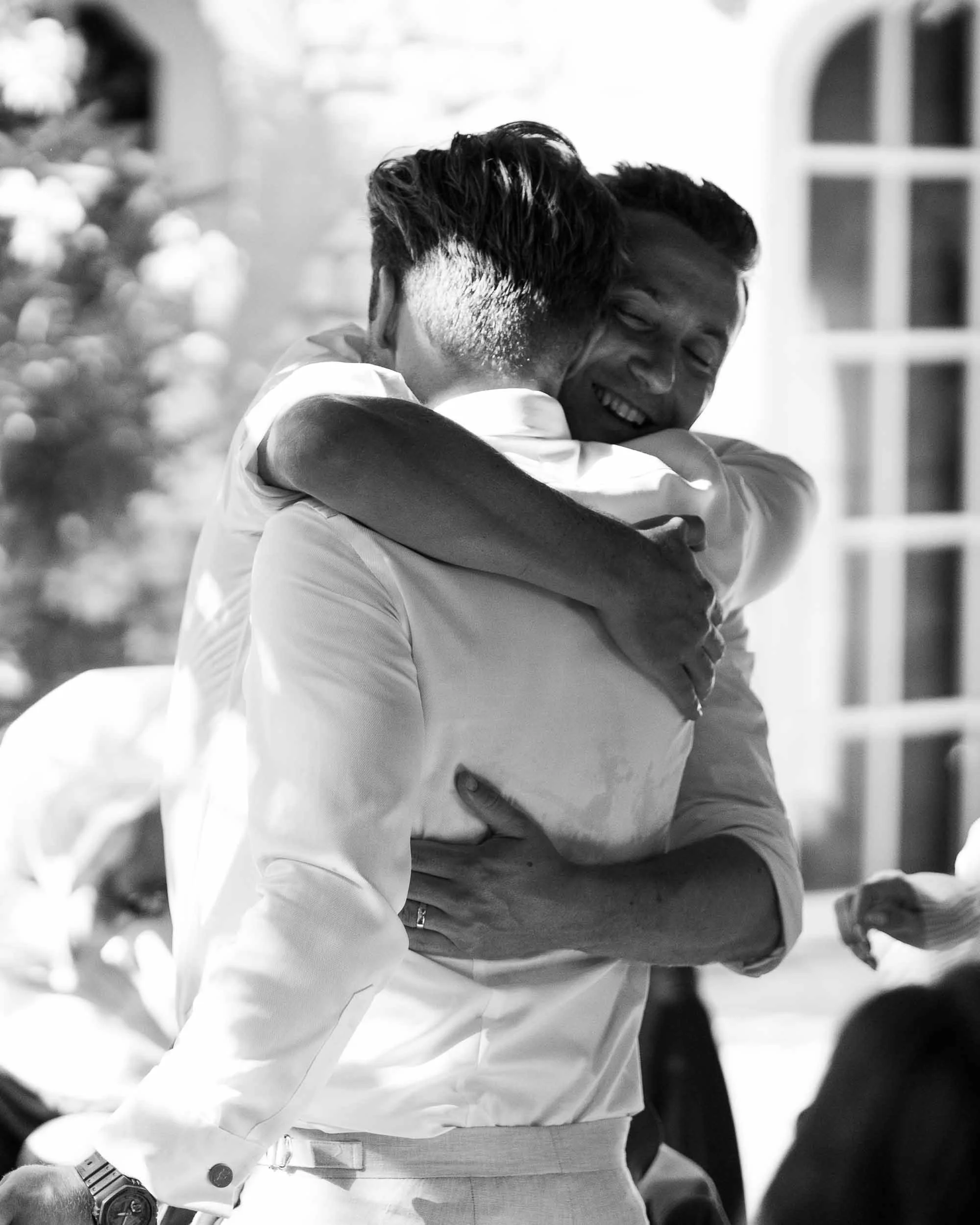 Black and white photograph of the groom hugging his best man