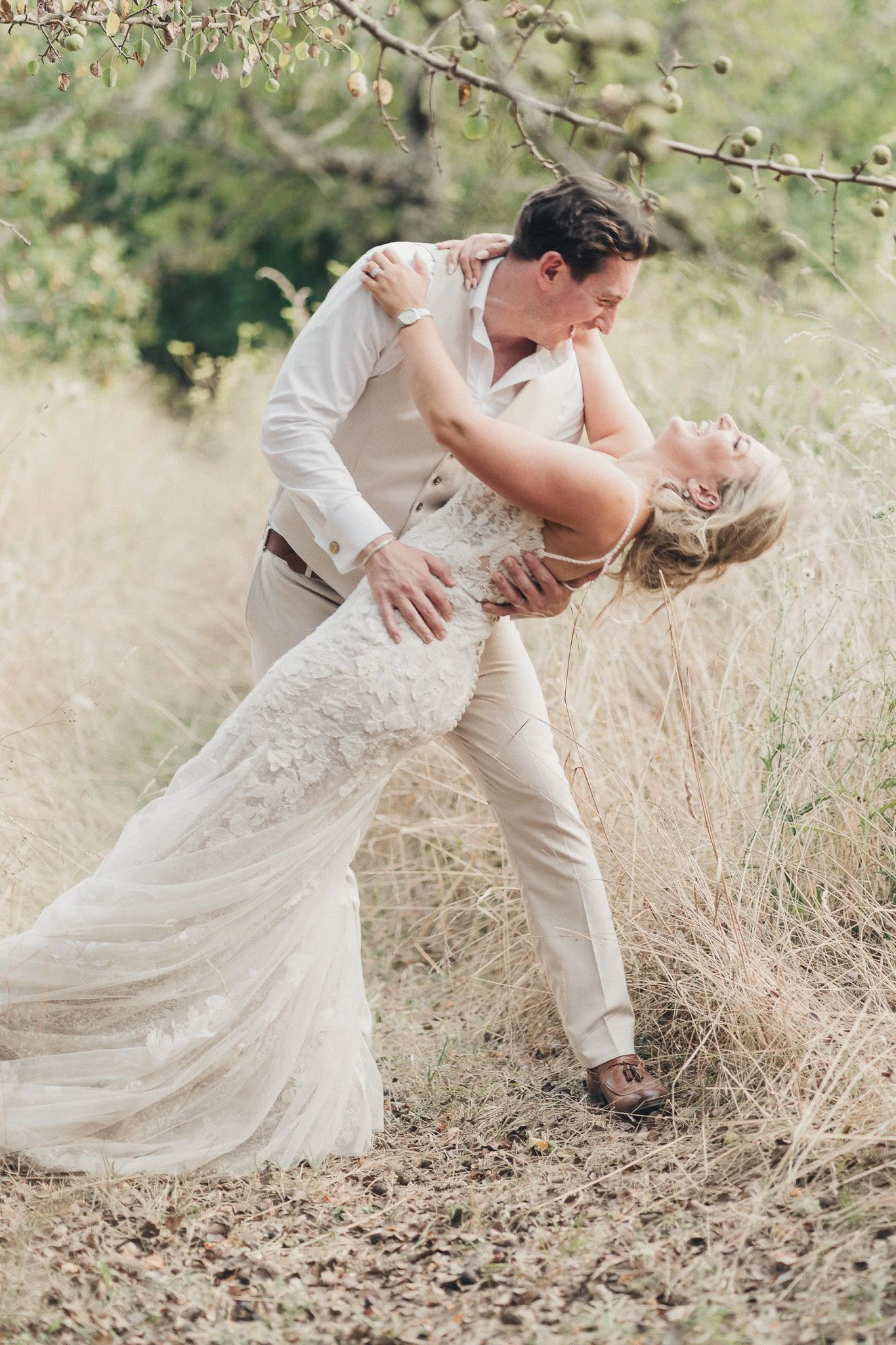 A playful portrait of the couple in tall grass during their wedding in the Dordogne