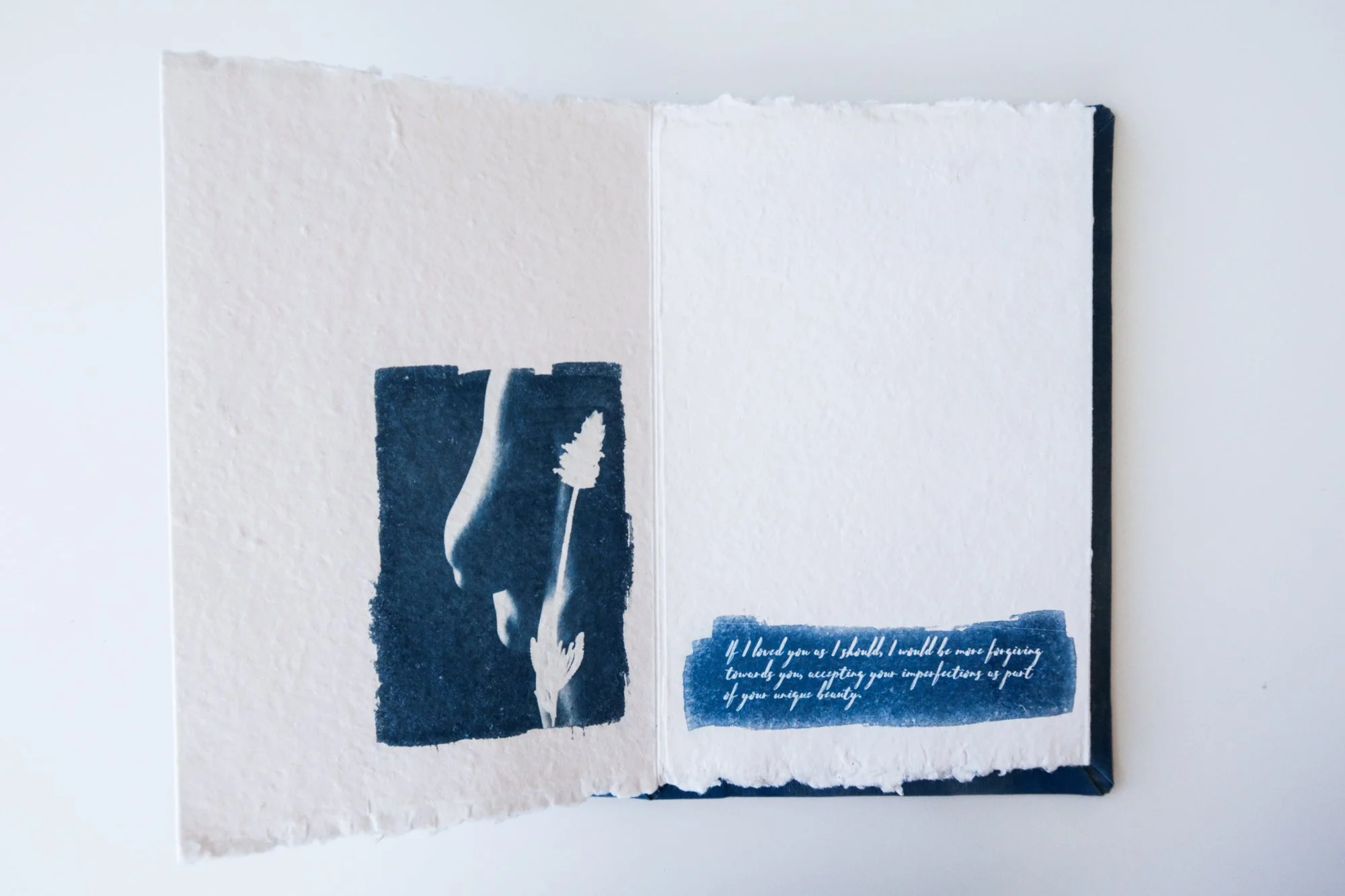 Page from a handmade artist book by Yanina Shevchenko, part of her project If I Loved You As I Should — a body-focused exploration of self-acceptance. Printed on handmade paper using cyanotype, the image combines body forms and natural elements