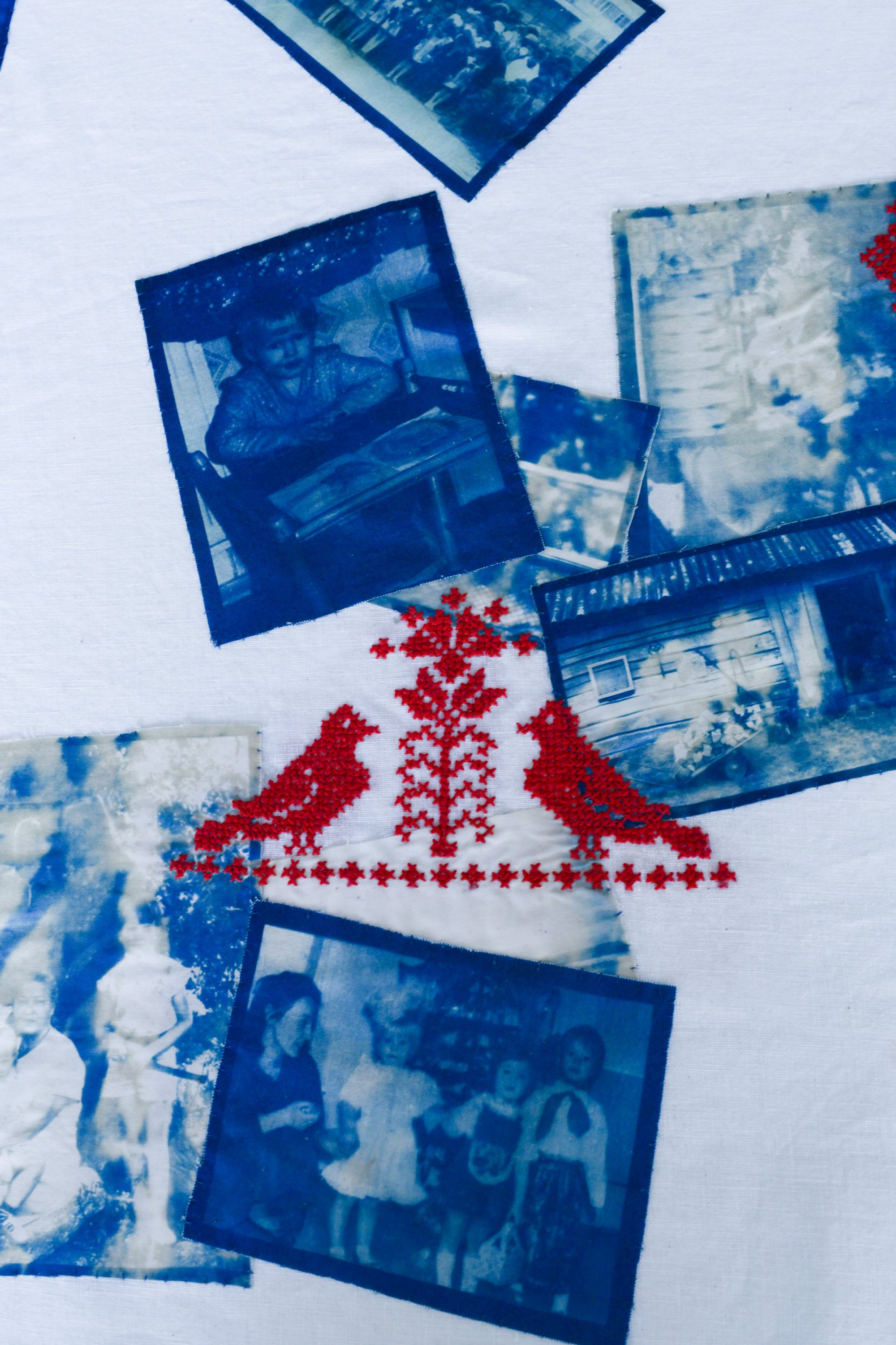 Black-and-white photographs of children in outdoor settings, placed on a surface with decorative red embroidery and snowflakes.