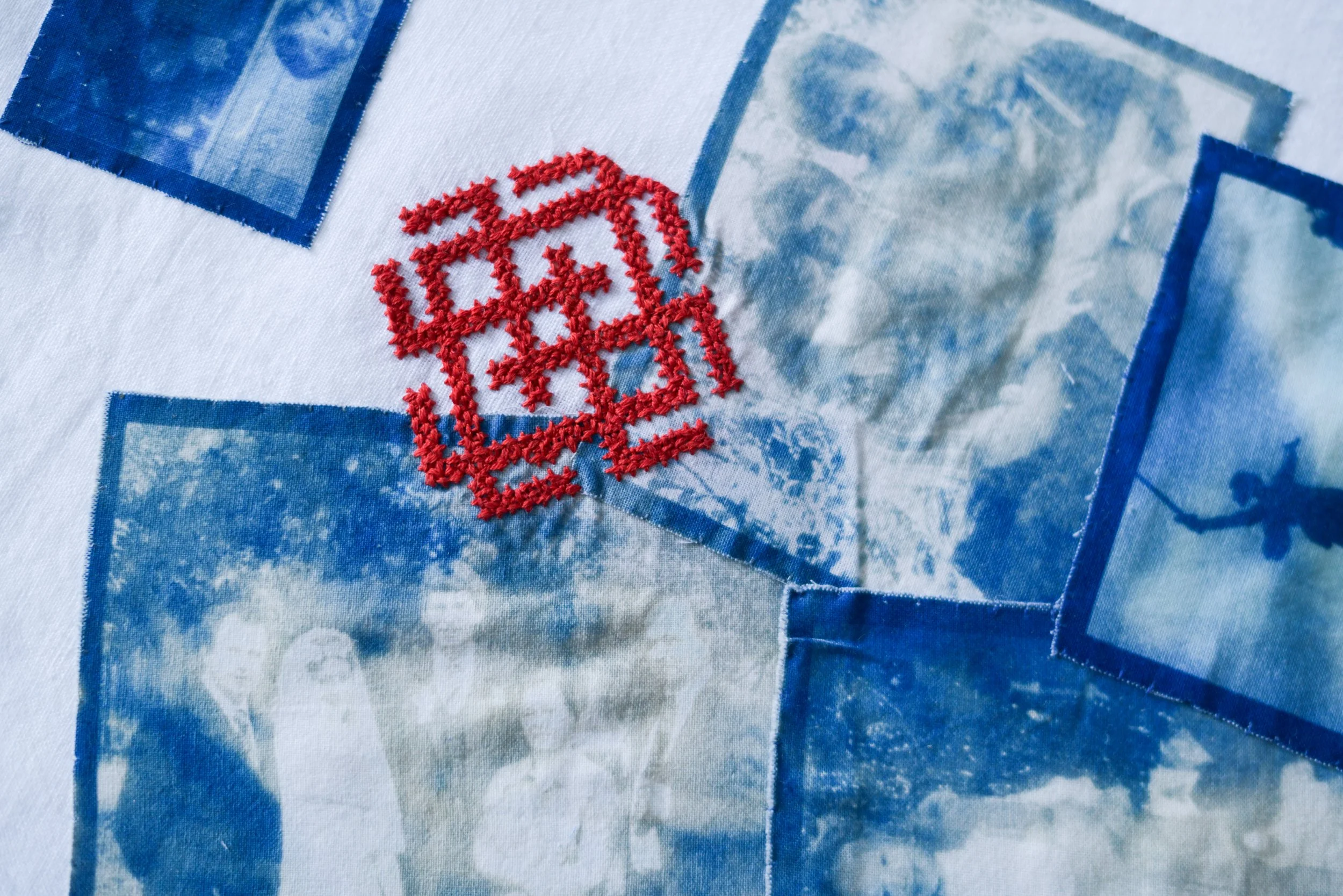 Close-up of a fabric with printed blue geometric patterns and embroidered red text that reads 'LOVE'.