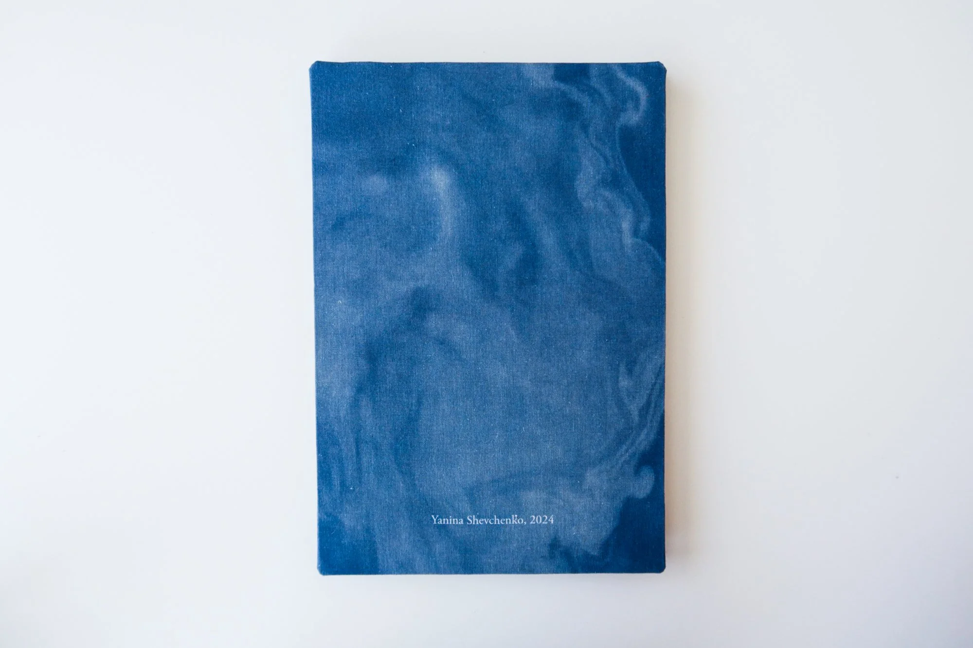 A blue book with a marbled pattern on the cover, titled by the author Yanina Shevchenko, dated 2024, placed on a white background.