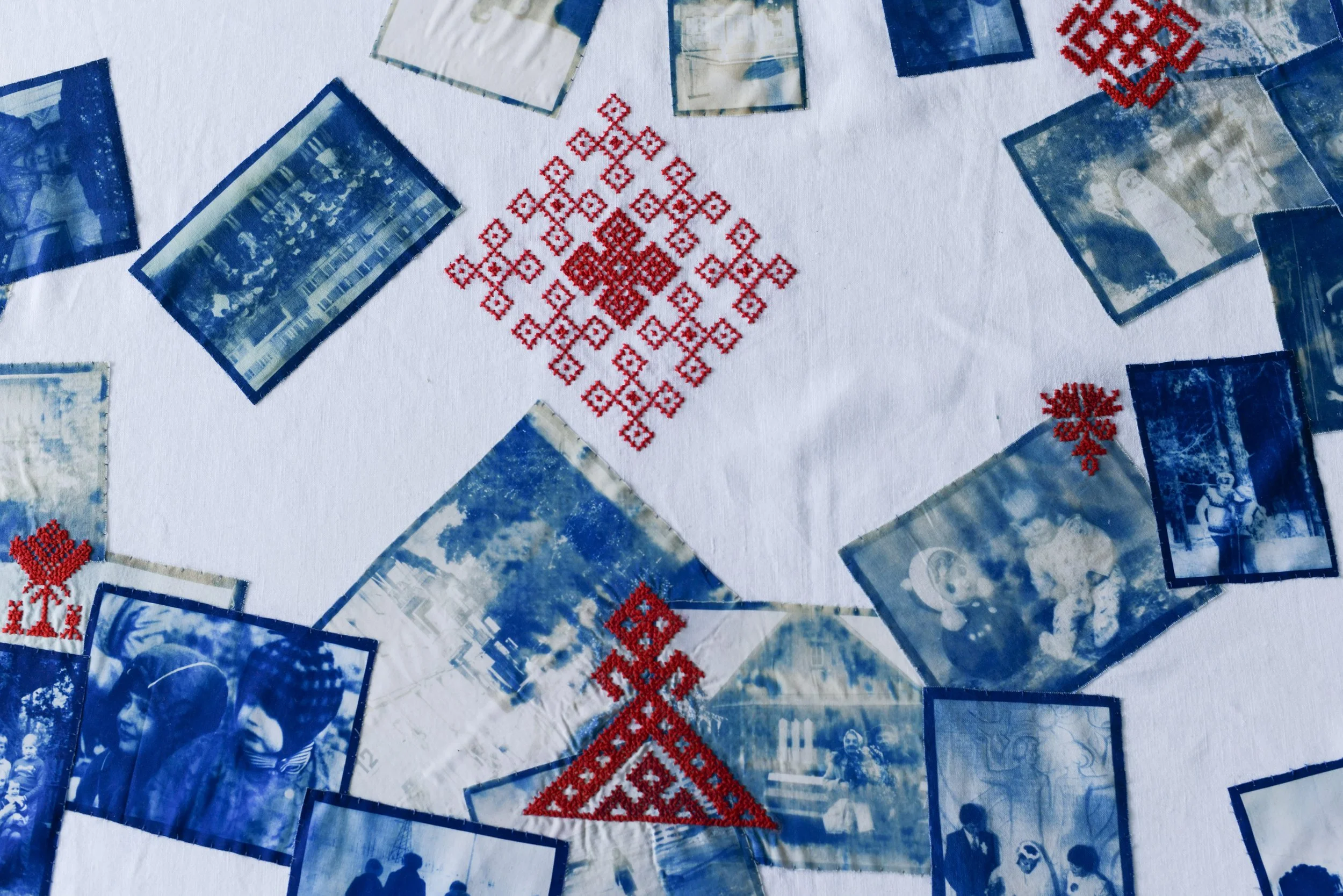A collage of blue-toned photographs and red embroidery. The photographs include images of buildings, people, and a snow scene. The red embroidery features snowflakes and geometric patterns, arranged in a symmetrical design.