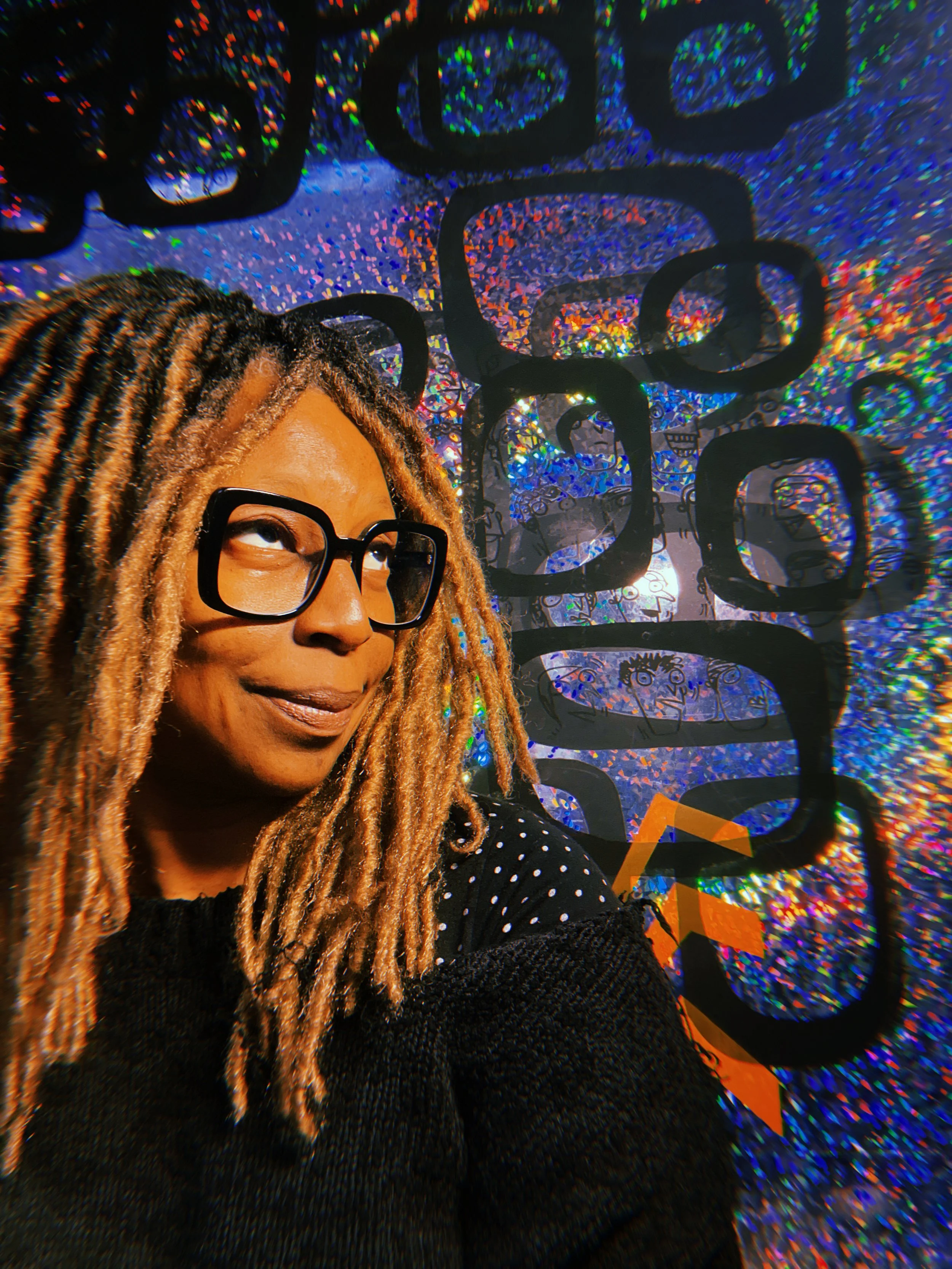 Woman with glasses and dreadlocks looking up, colorful background with abstract shapes and patterns.