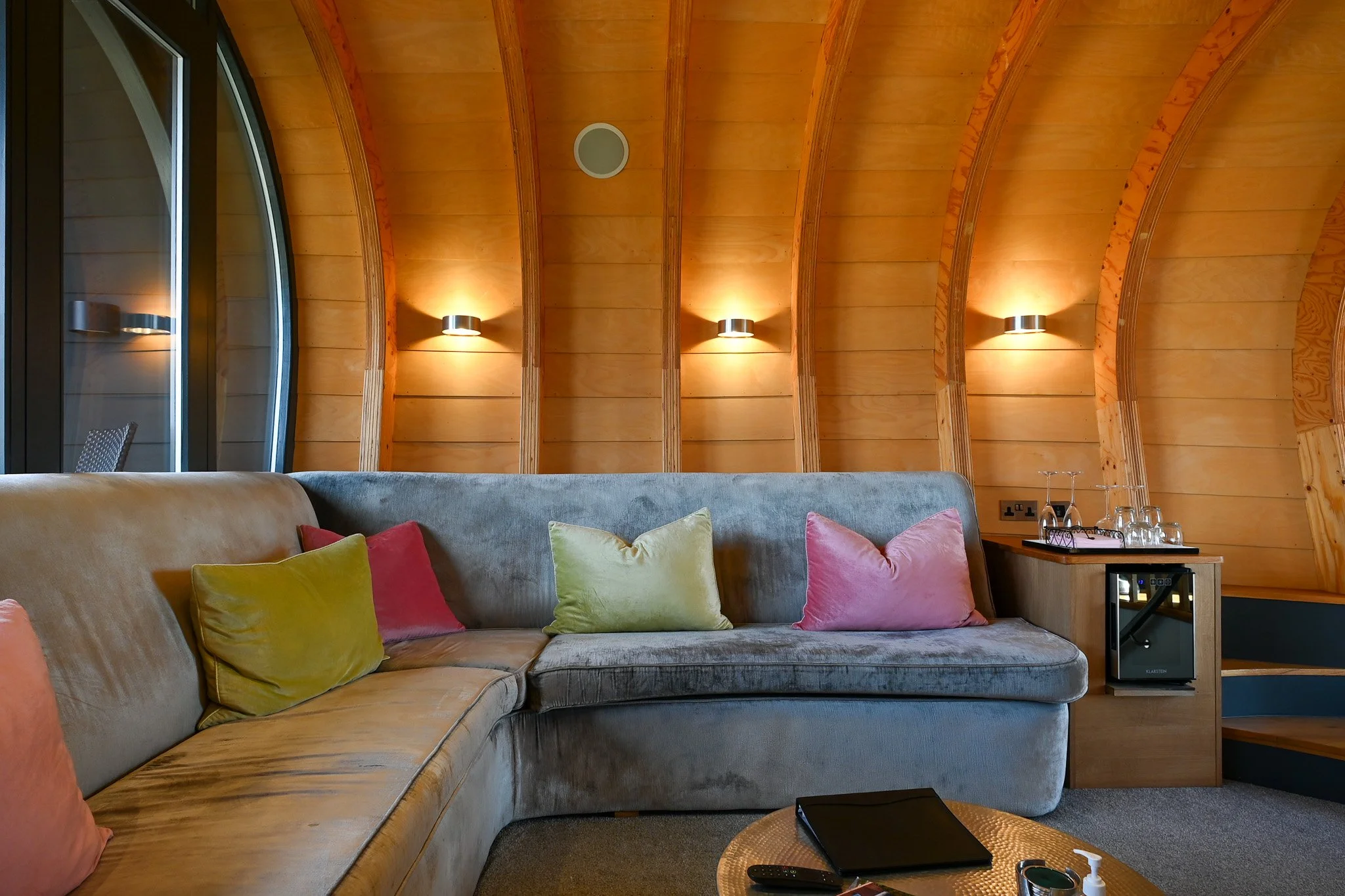 inside the pod at the windmill suffolk, with timber beams and a grey sofa