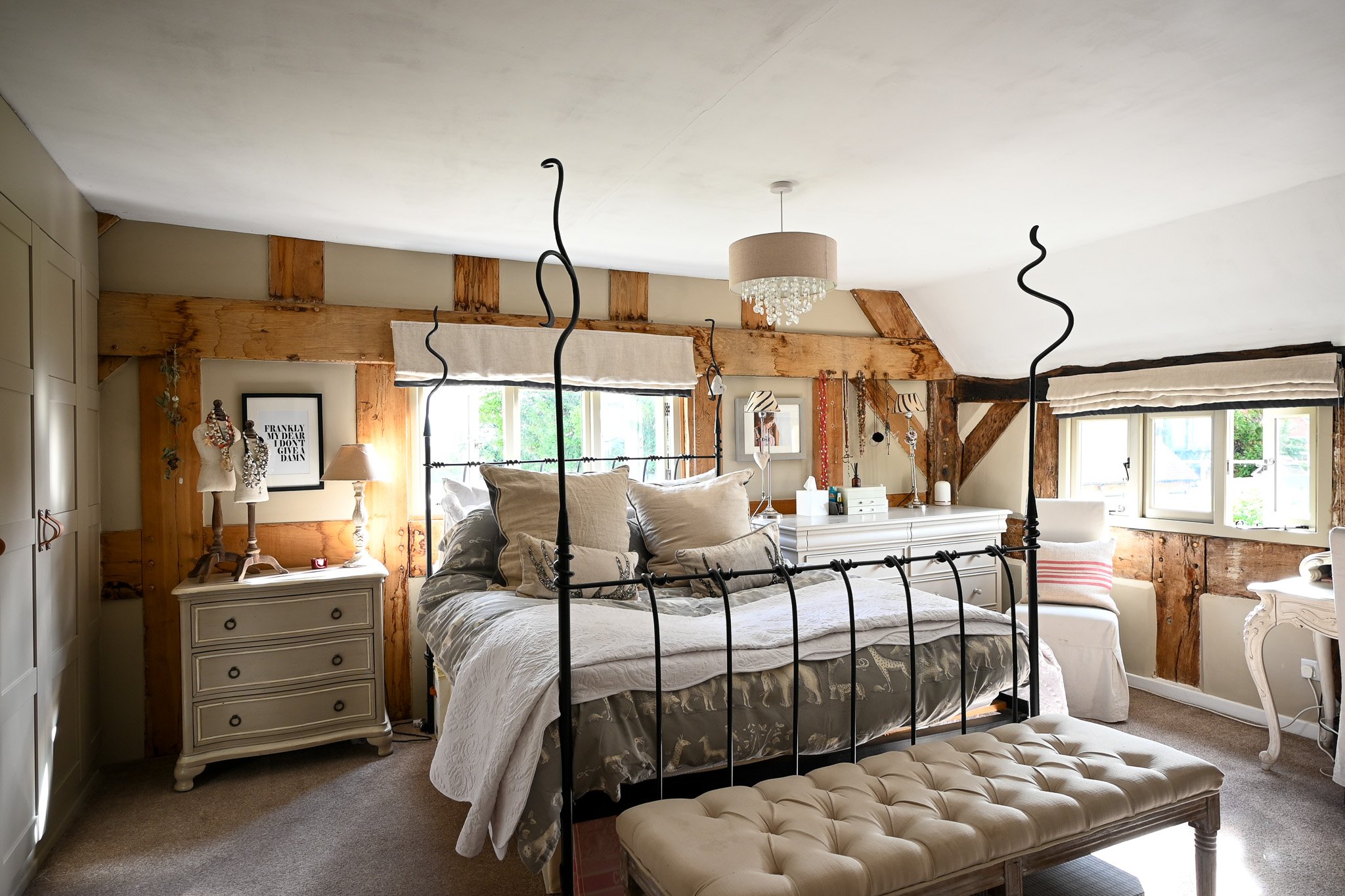 main bedroom within cottage with large wooden beams on the wall and a double bed