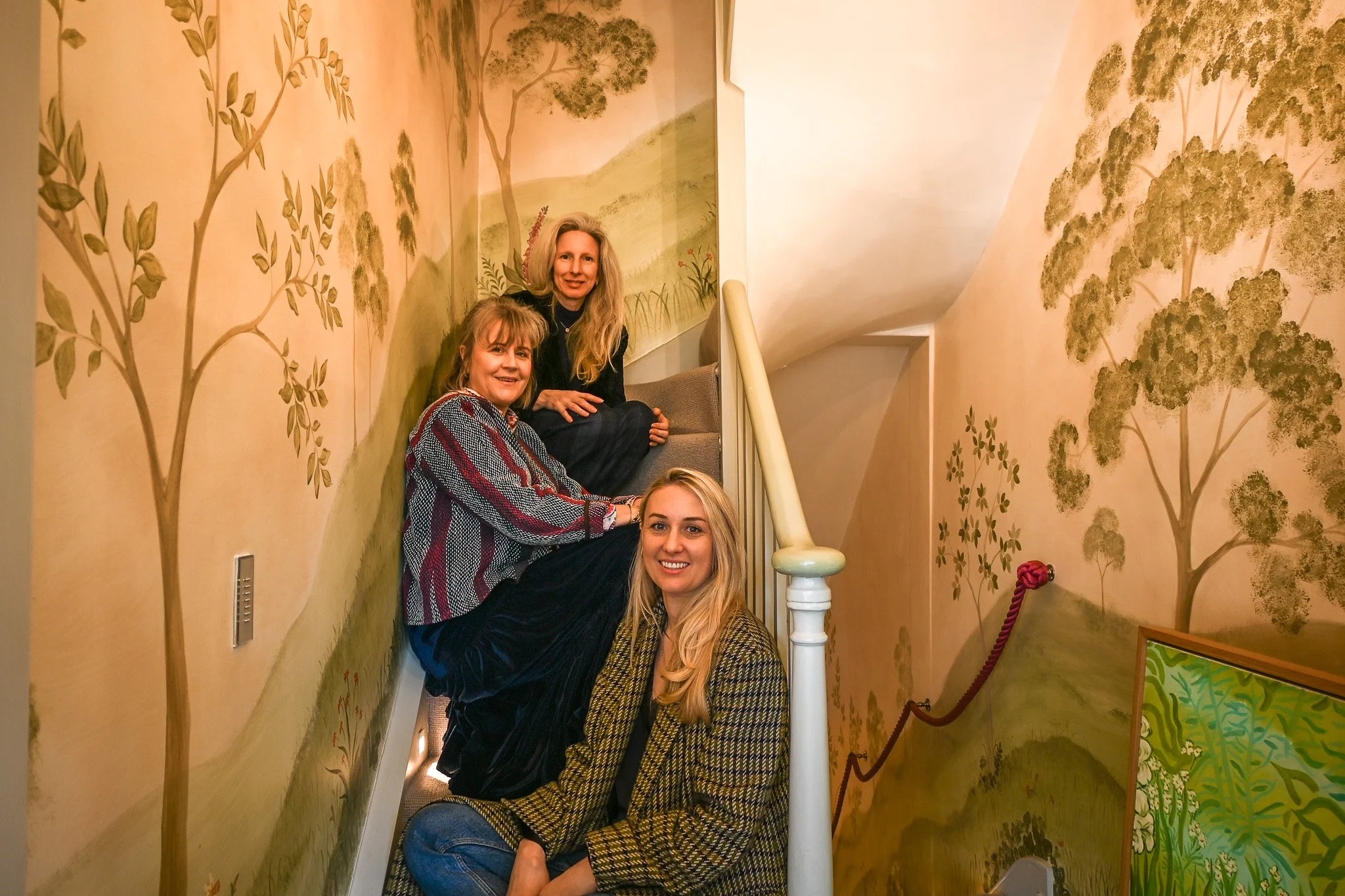 3 interior designers sitting on staircase in hallway