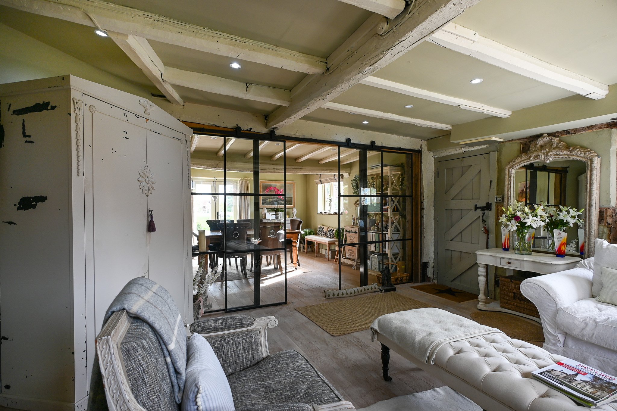 living room going into the dining room with large glazed sliding doors and timber beams above