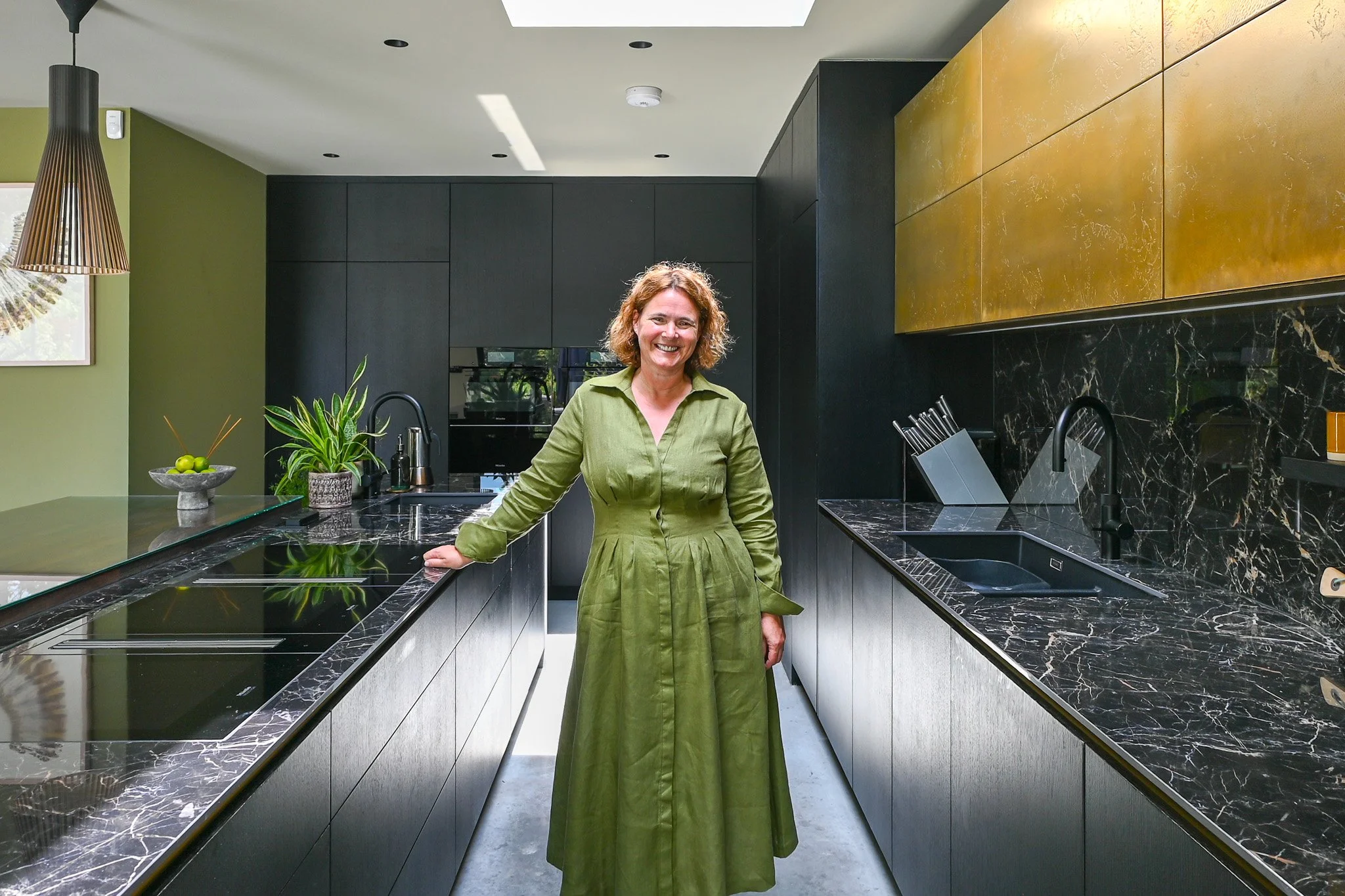 women in green dress standing in a gold and black kitchen