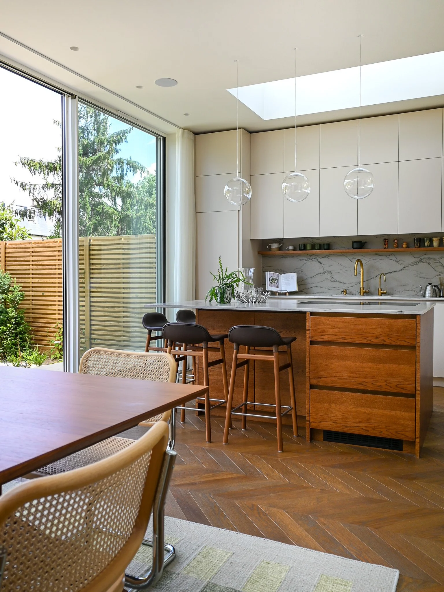 kitchen island with marble worktop and bar stools, hanging lights and a sliding door