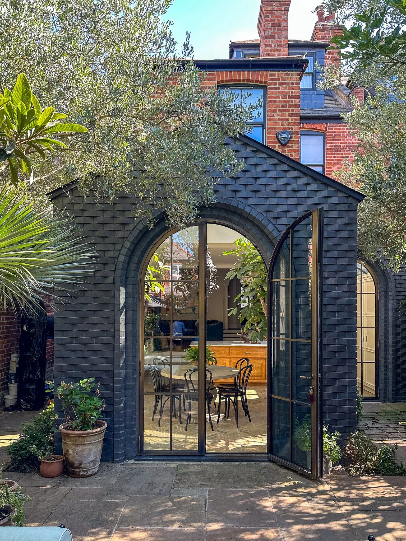 rear elevation of london home with black woven brickwork with double arched bronze doors