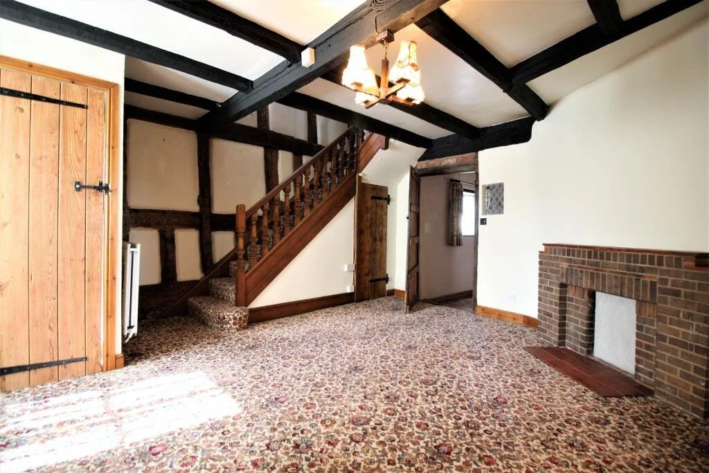 living room with carpet and dark staircase and dark timber beams