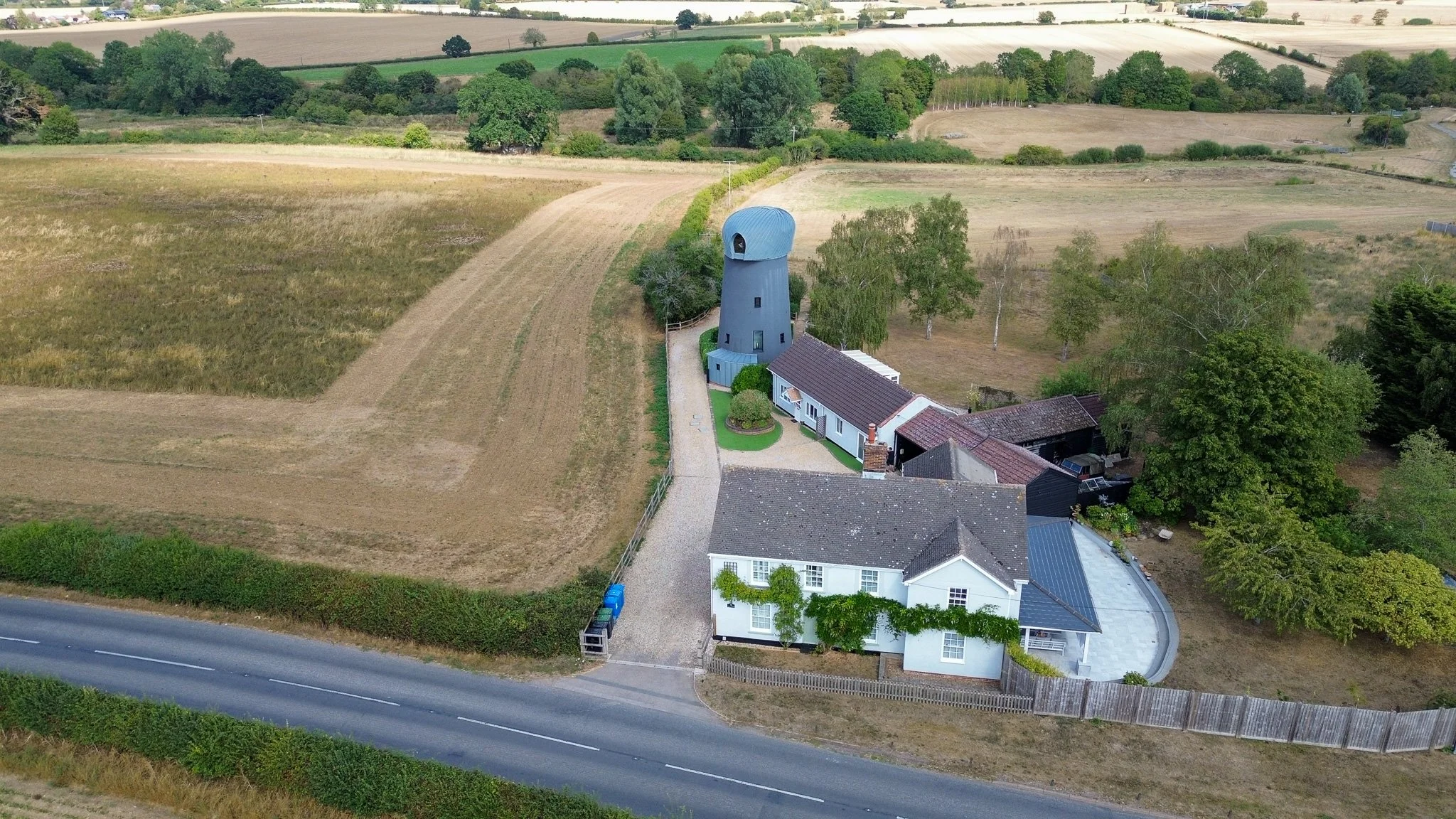 an aerial shot of a converted windmill by the main road