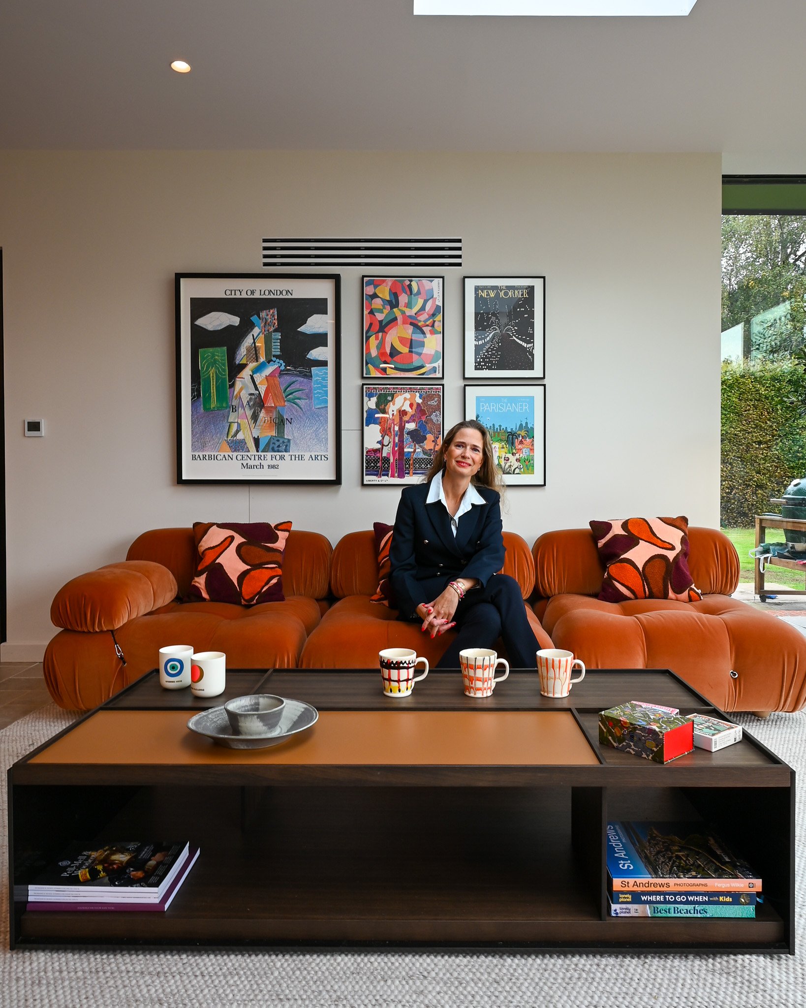 women sitting on a red mid century sofa in a kitchen extension with a modern coffee table