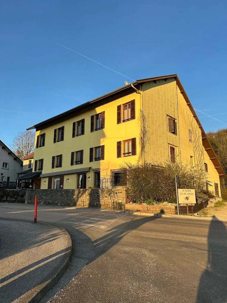 Un bâtiment résidentiel jaune avec des volets en bois, sous un ciel bleu clair.