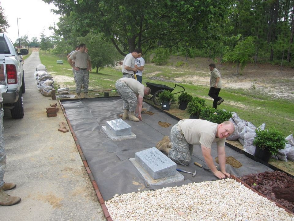 A group of people in military uniforms working together to lay small white stone around the memorials on the 3rd Special Forces Group Memorial Walk.