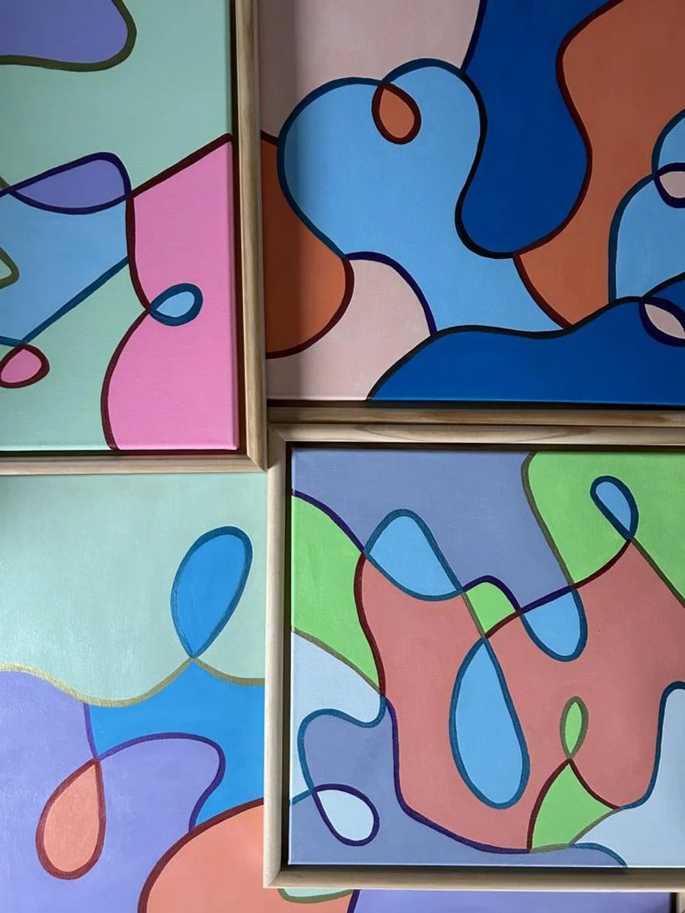 Abstrakte, bunte Gemälde mit organischen Formen und Linien in Pastellfarben, in Rahmen präsentiert.