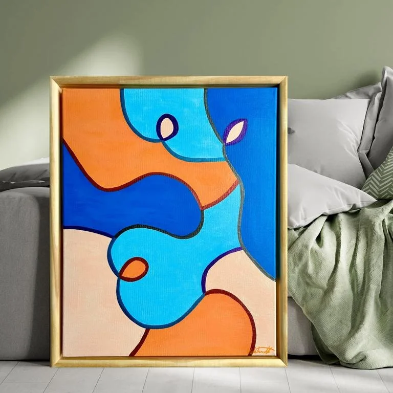 Abstraktes farbiges Gemälde mit geometrischen Formen in Blau, Orange und Beige, gerahmt, steht vor einem Sofa mit Kissen im Raum.