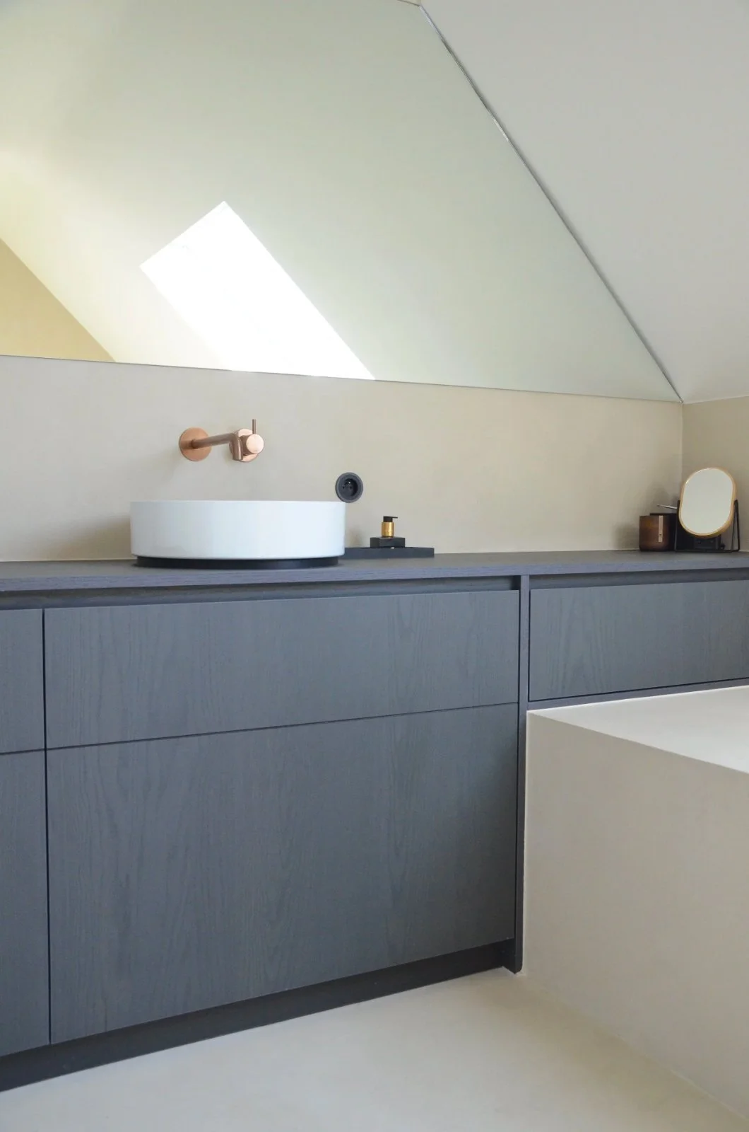 Gerenoveerde badkamer onder een schuin dak met donker meubel en koperen kraanwerk, project door Atelier Ombre
