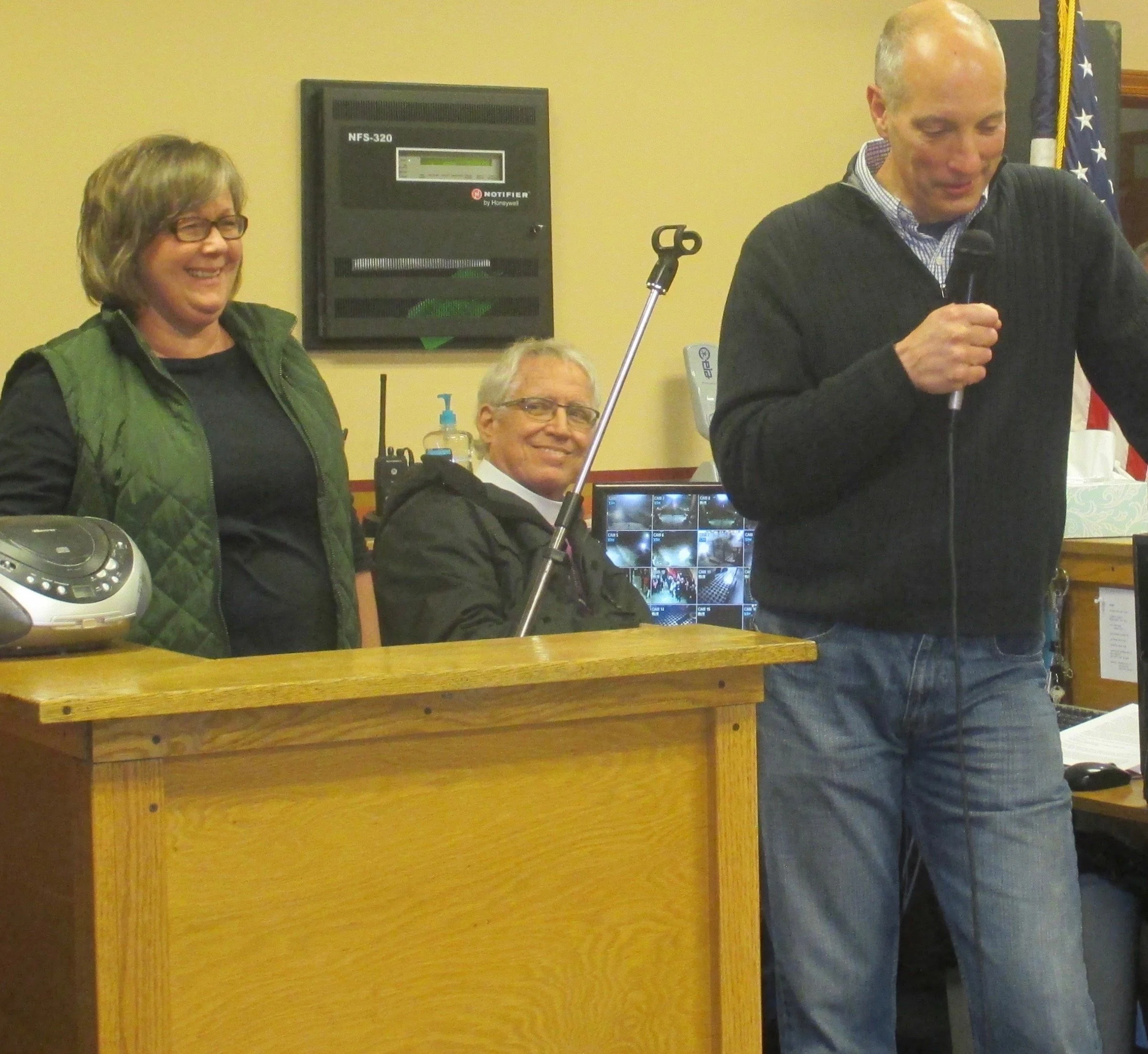 Shelby County Right to Life Candlelight Vigil for remembering the Unborn and Aborted; A man holding a microphone, York, leading a meeting or prayer with two people sitting at a desk, a woman smiling and a man watching with a camera monitor behind.