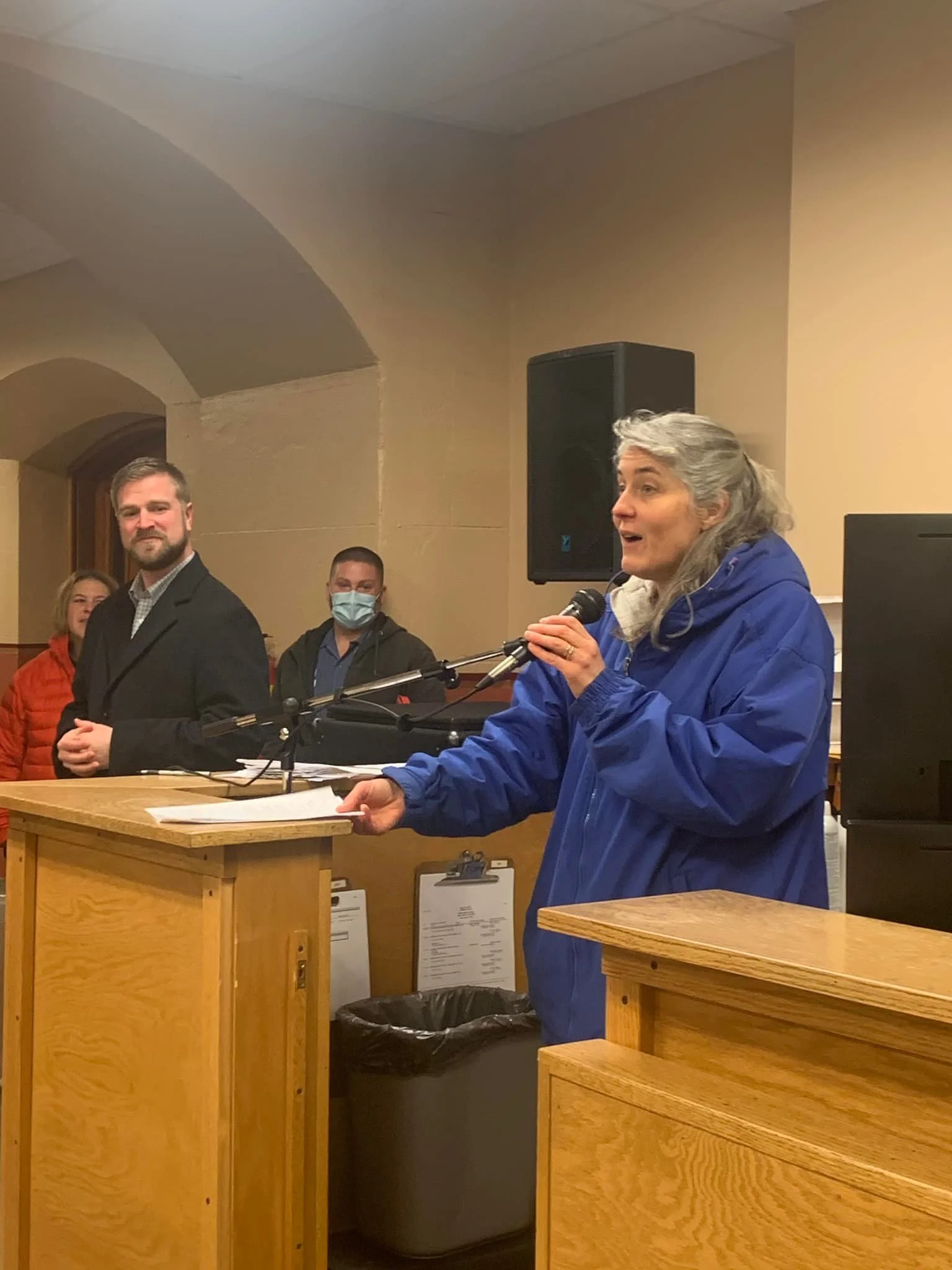 A woman speaking into a microphone at a podium during a candlelight vigil for the unborn.