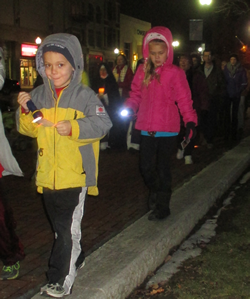 Shelby County Right to Life Candlelight Vigil for remembering the Unborn and Aborted; Two children walking on a city sidewalk at night, wearing winter jackets and hoodies, with one child holding a glow stick.